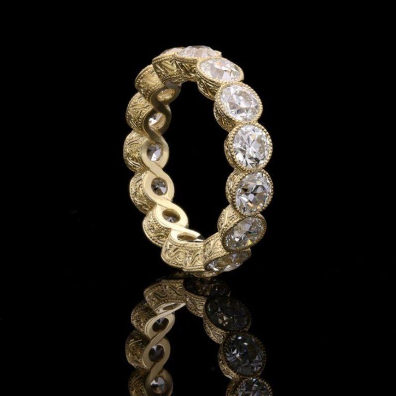 A stunning diamond full eternity ring set with fifteen old European cut diamonds weighing a total of 4.90cts, rub over set in a finely crafted 18ct yellow gold mount with millegrain edging and beautiful hand engraved scroll details to the