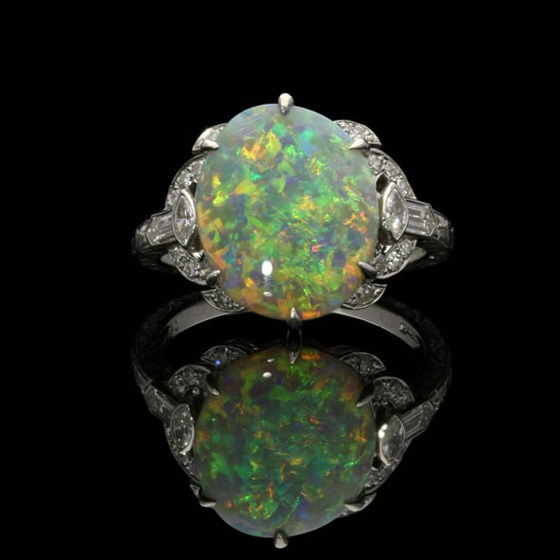 Beautiful opal and diamond ring by Hancocks, set to the centre with an oval opal cabochon weighing 2.95 carats and with attractive play of colour claw set between diamond shoulders set with marquise, bullet and single-cut diamonds to a finely hand