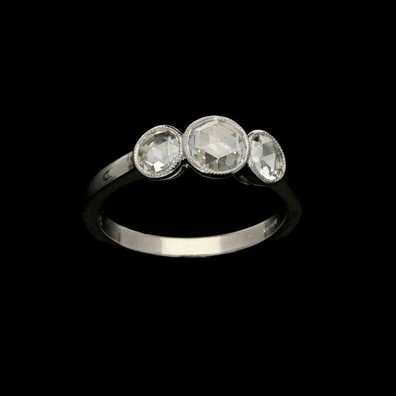 A pretty three-stone diamond and platinum ring by Hancocks set with three rose cut diamonds weighing a combined total of 1.21cts, all rubover set in platinum with millegrain edges to a handcrafted mount with simple D-section