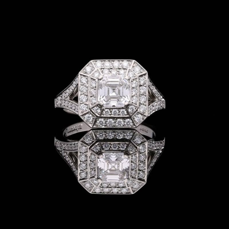 A vintage Asscher cut diamond and platinum ring by Hancocks, set to the centre with a beautiful Asscher cut diamond weighing 0.91ct and of D colour and VVS2 clarity, corner claw set within a geometric double halo surround of round brilliant cut