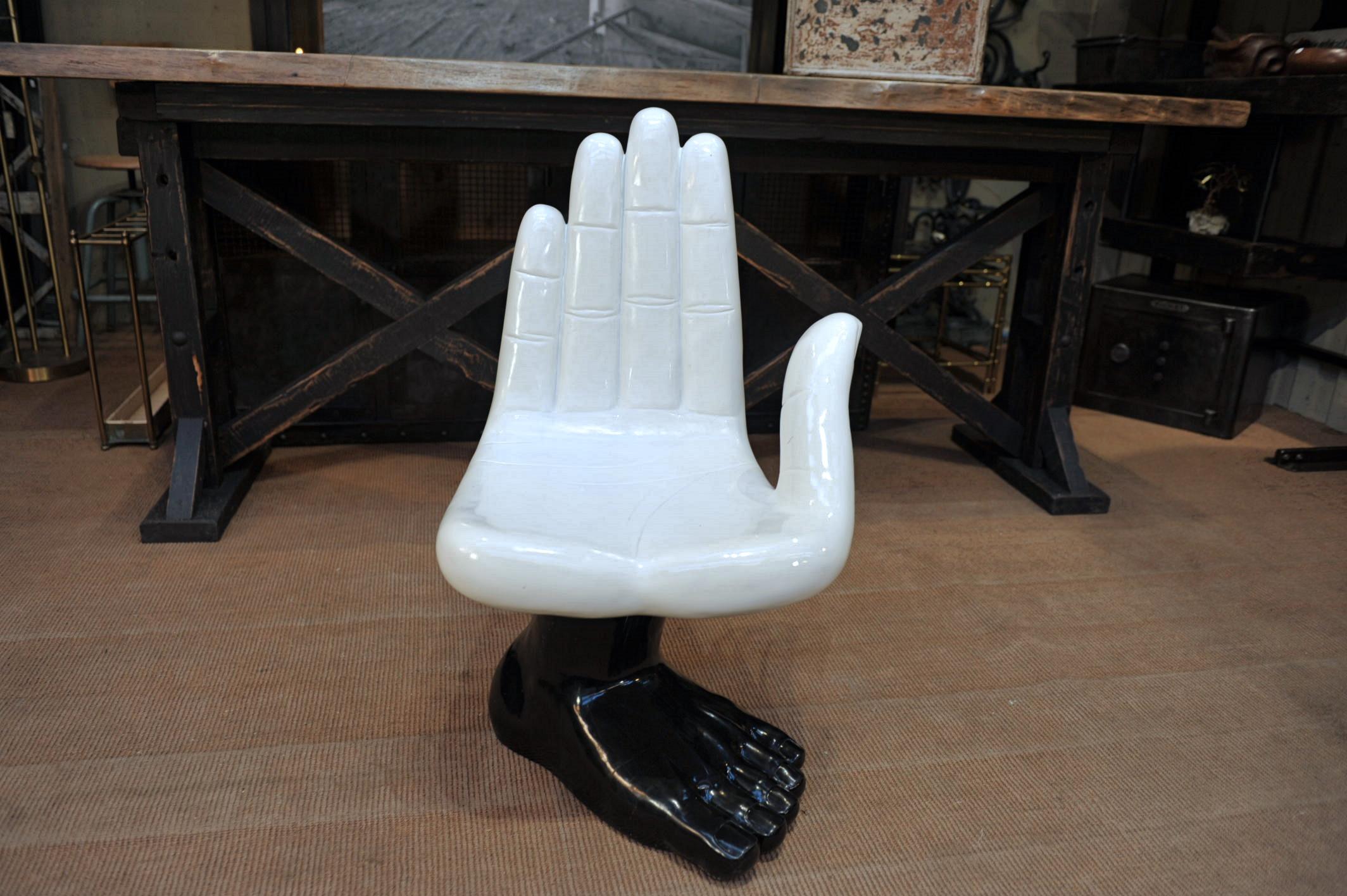 Chaise pivotante en résine avec un grand siège blanc en forme de main tournant sur une base noire en forme de pied, vers 1970, poids 32 kg.