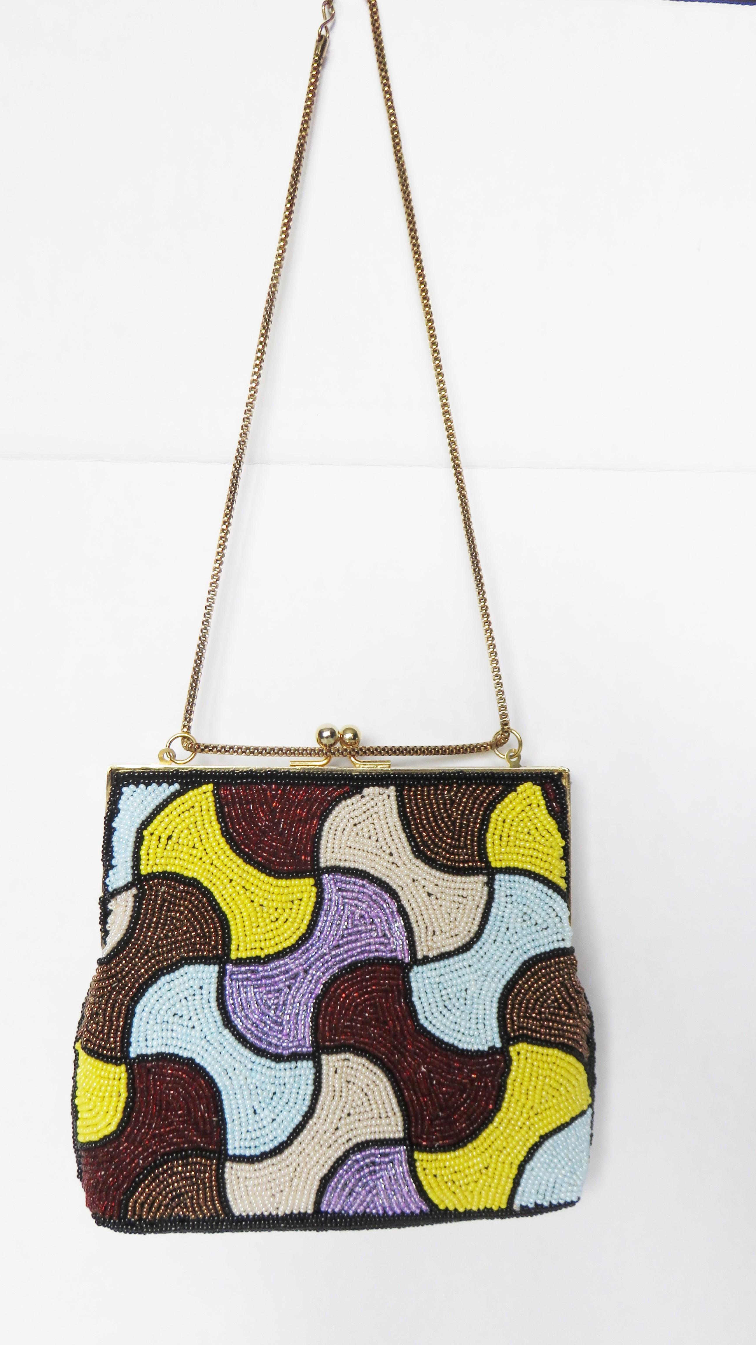 A fabulous brightly colored handbag in a lilac, burgundy, light blue, yellow and bronze glass beaded abstract pattern on both sides. It has a top gold metal ball clasp and frame plus a mesh snake chain top handle which can be worn on the shoulder,
