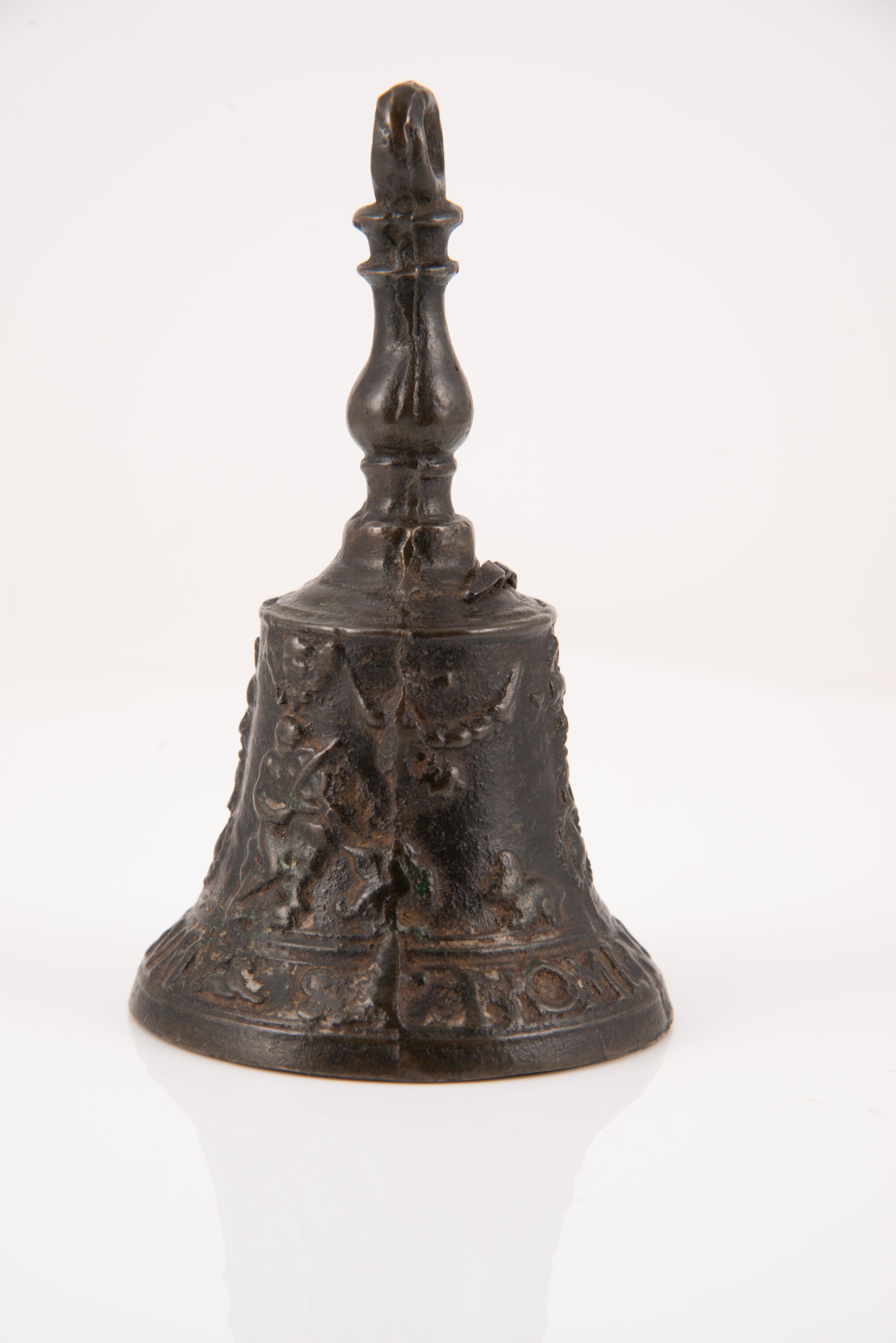 Hand bell or bell, “from Malinas”. Bronze. 16th century. 
Hand bell with clapper made of bronze and decorated on the outside with a slight relief. The base has, between bands, an inscription in capital letters and in Latin (“Sit nomen Domini