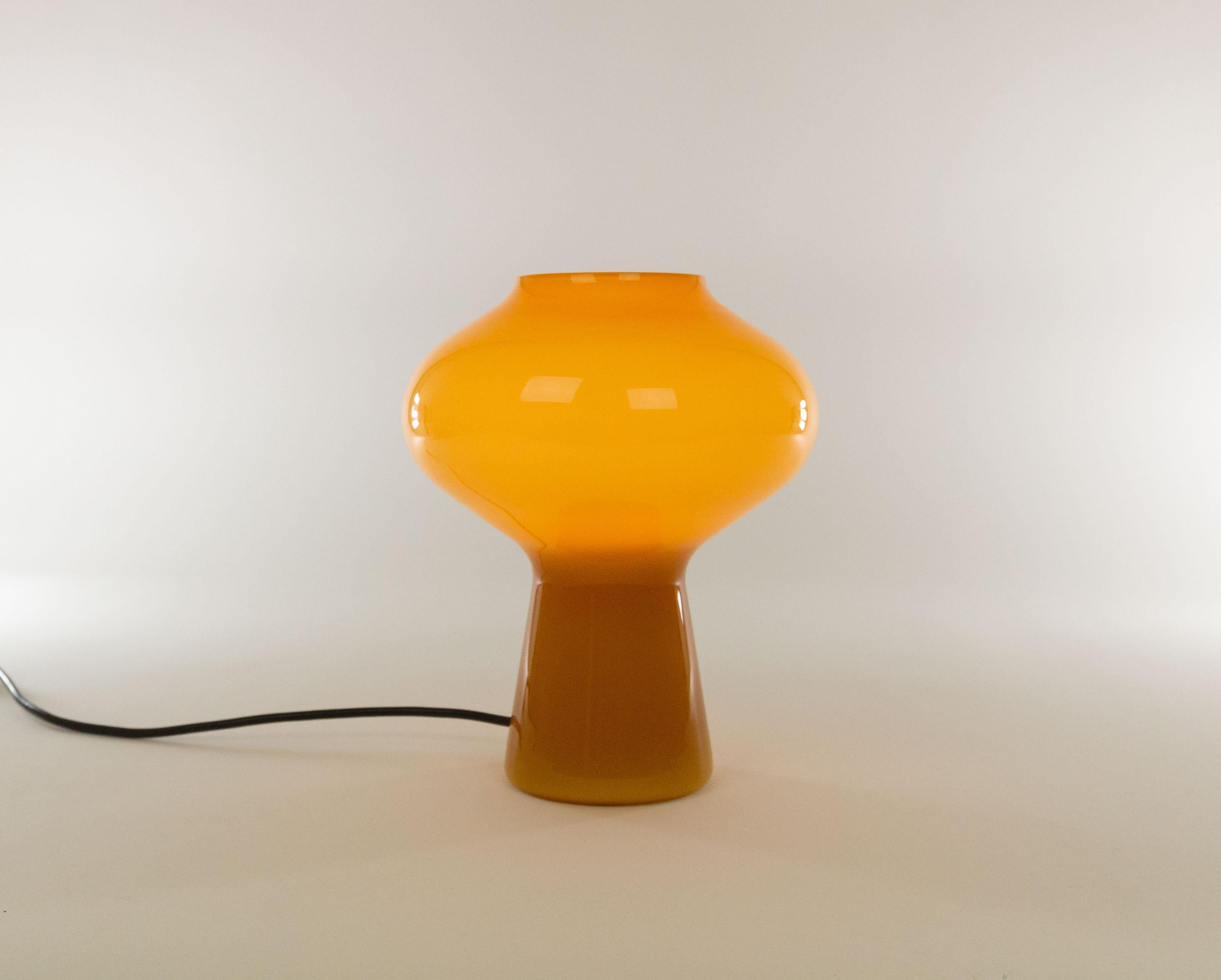 Lampe de table Fungo en verre ambré soufflé à la main, conçue par Massimo Vignelli au début de son impressionnante carrière de designer et exécutée par Venini, spécialiste du verre de Murano. 

C'est la version moyenne haute. Veuillez noter que la