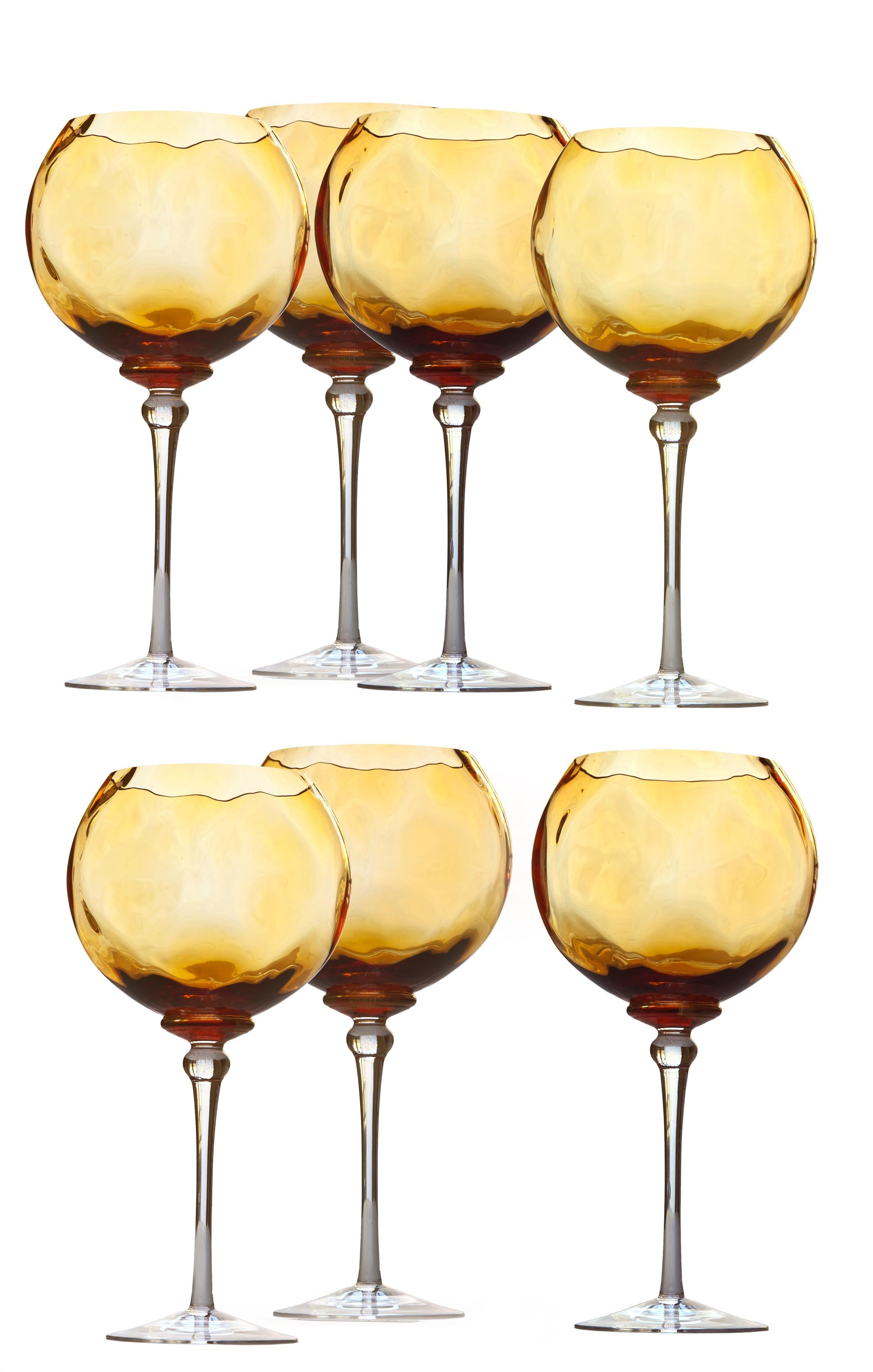 Striking set of 7 red wine goblets are made from beautiful hand-blown amber glass. Extra large globes make a stunning statement on any table, and feature an undulating pattern with gold leaf accents at the base. Clear stems. Each glass has been