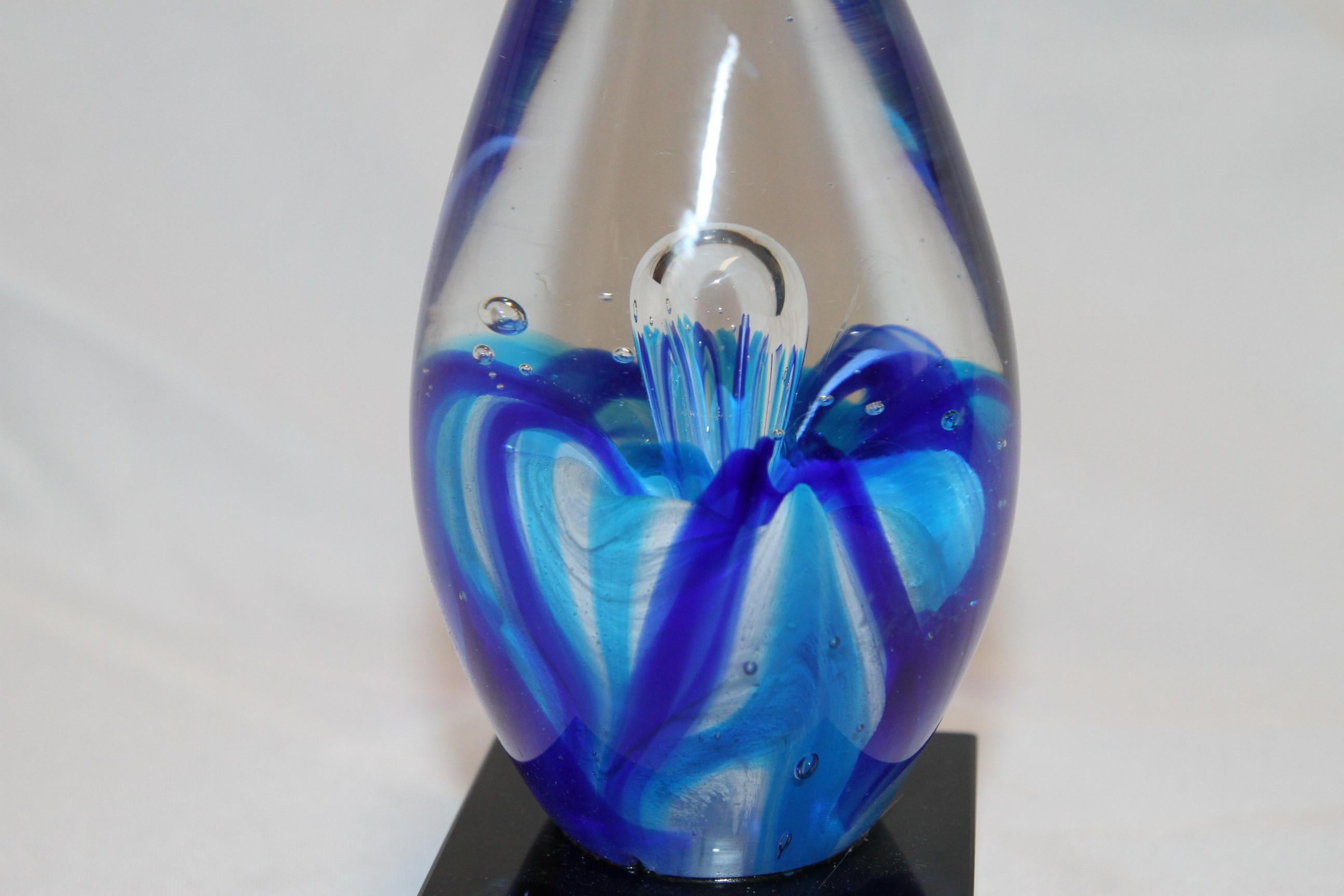 Cette belle pièce de verre d'art est livrée avec sa boîte. Le verre présente des tourbillons bleus. 
Les bulles dans le verre vous permettent de savoir qu'il a été soufflé à la main.