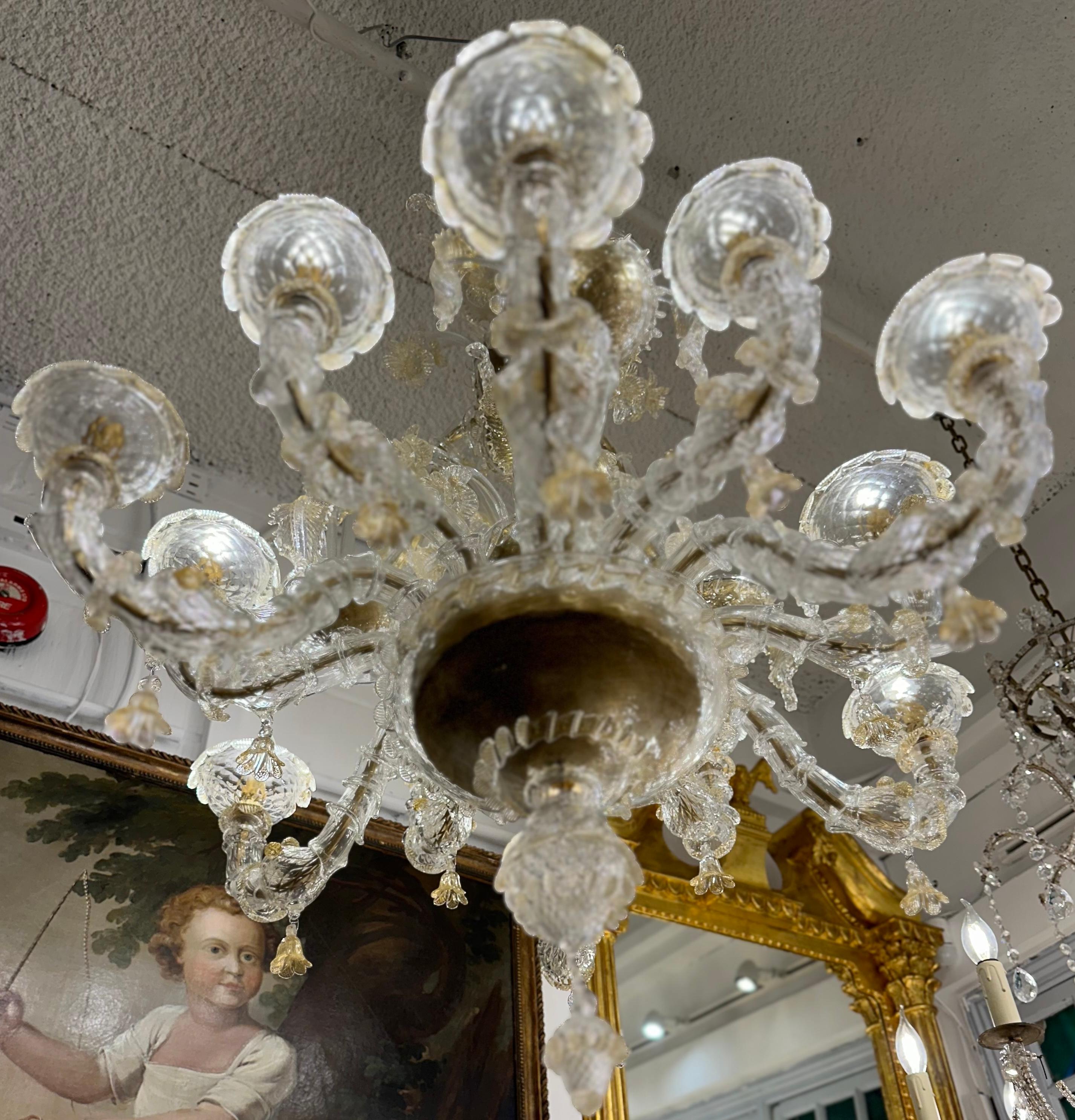 A magnificent hand blown murano glass chandelier that is exquisite in its craftsmanship and design. Clear and 24 kt gold leaf has been added into the hand blown glass, which is formed into delicate foliage and bell like flowers lending a ethereal,