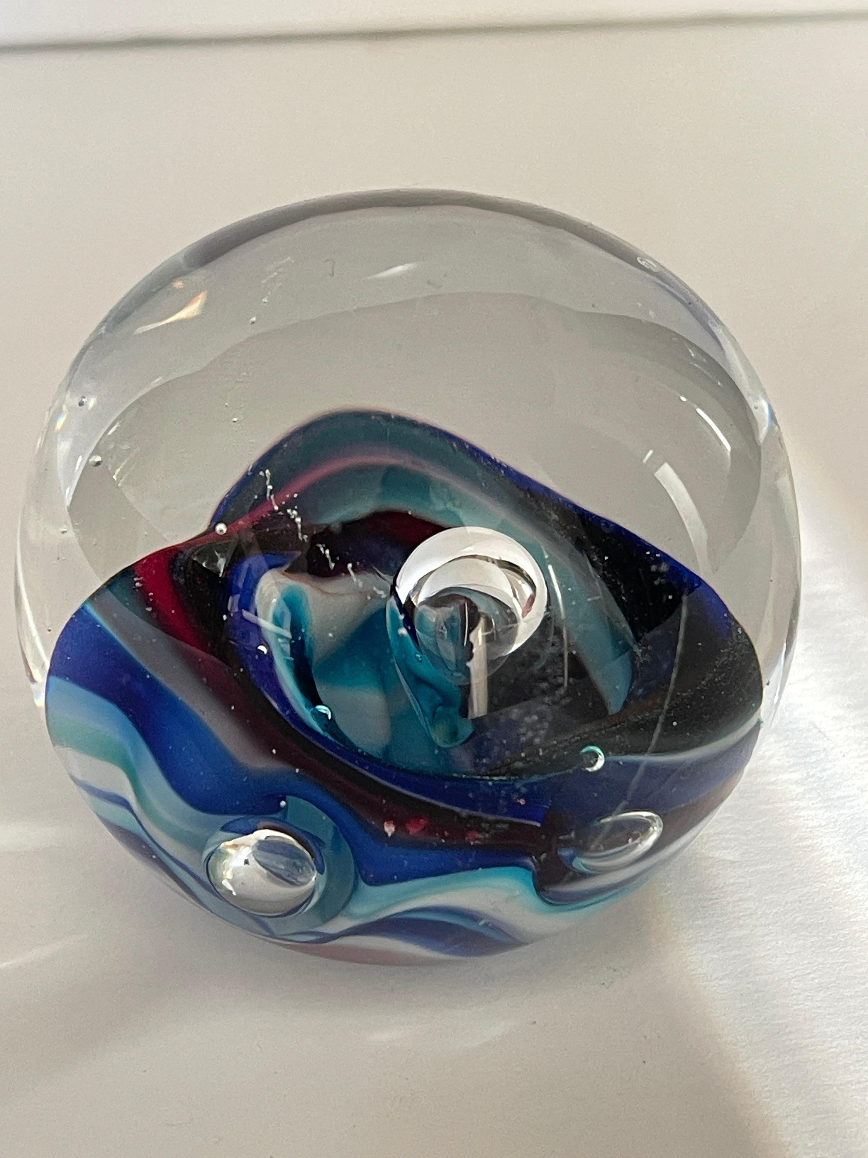 Briefbeschwerer aus mundgeblasenem Glas mit einer Meereswelle in den Farben Türkis, Indigo, Himmelblau, Kadettblau und einer purpurnen Bandwelle.
Eingravierte Signatur Karg, am unteren Rand.