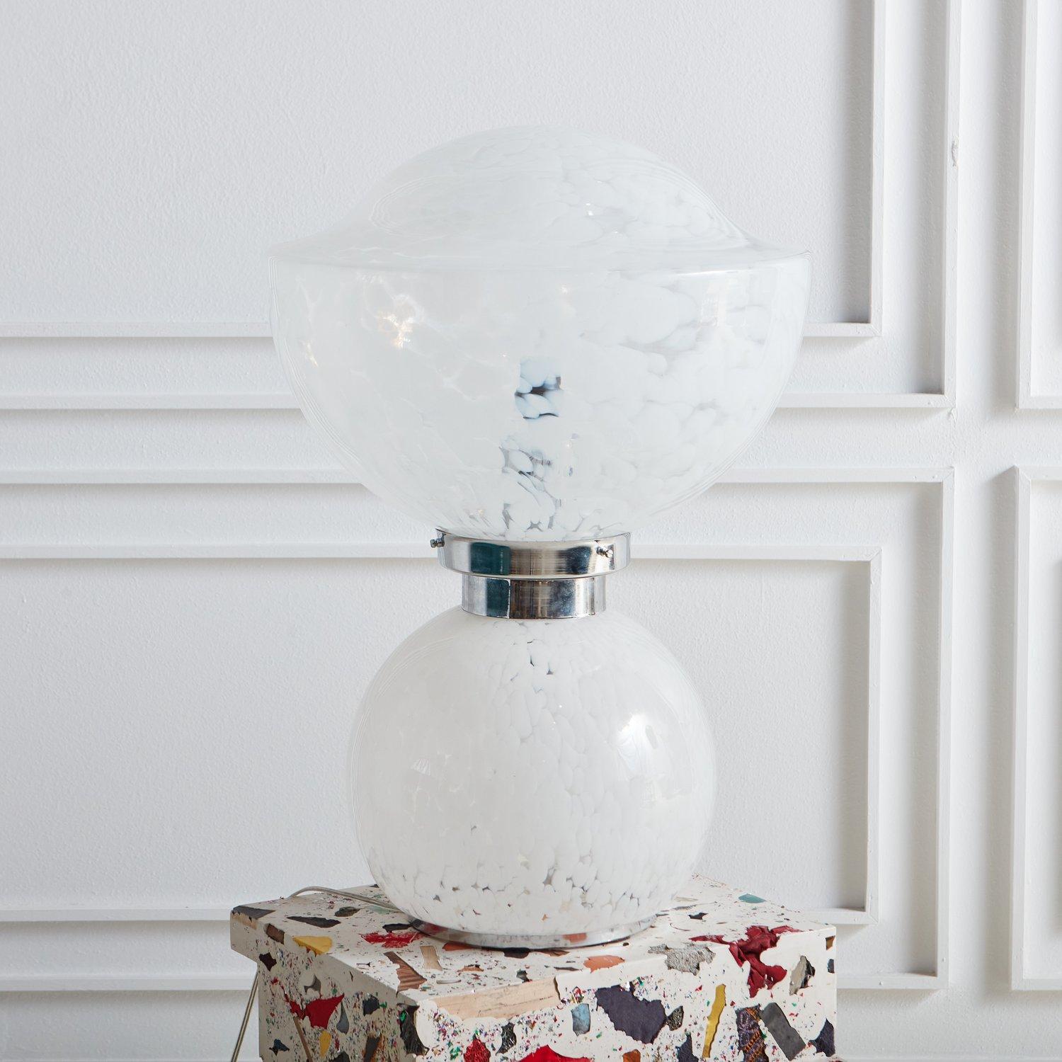 A sculptural vintage table lamp in the style of Carlo Nason. This lamp is composed of two clear hand blown glass globes with clouded white detailing. It has a circular chrome base and chrome center support. When lit, this beauty emanates a warm