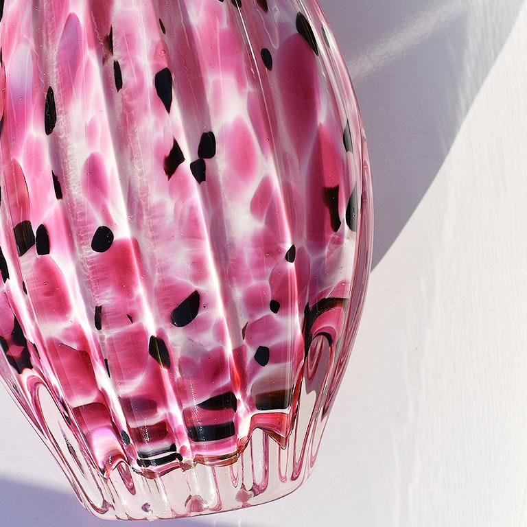 A beautiful hand-blown art glass pitcher. In pink, black, and white, the color pattern reminds us of one of our favorite ikat fabrics. The interior of the pitcher is white, and the exterior features a clear glass over the pattern. The handle has