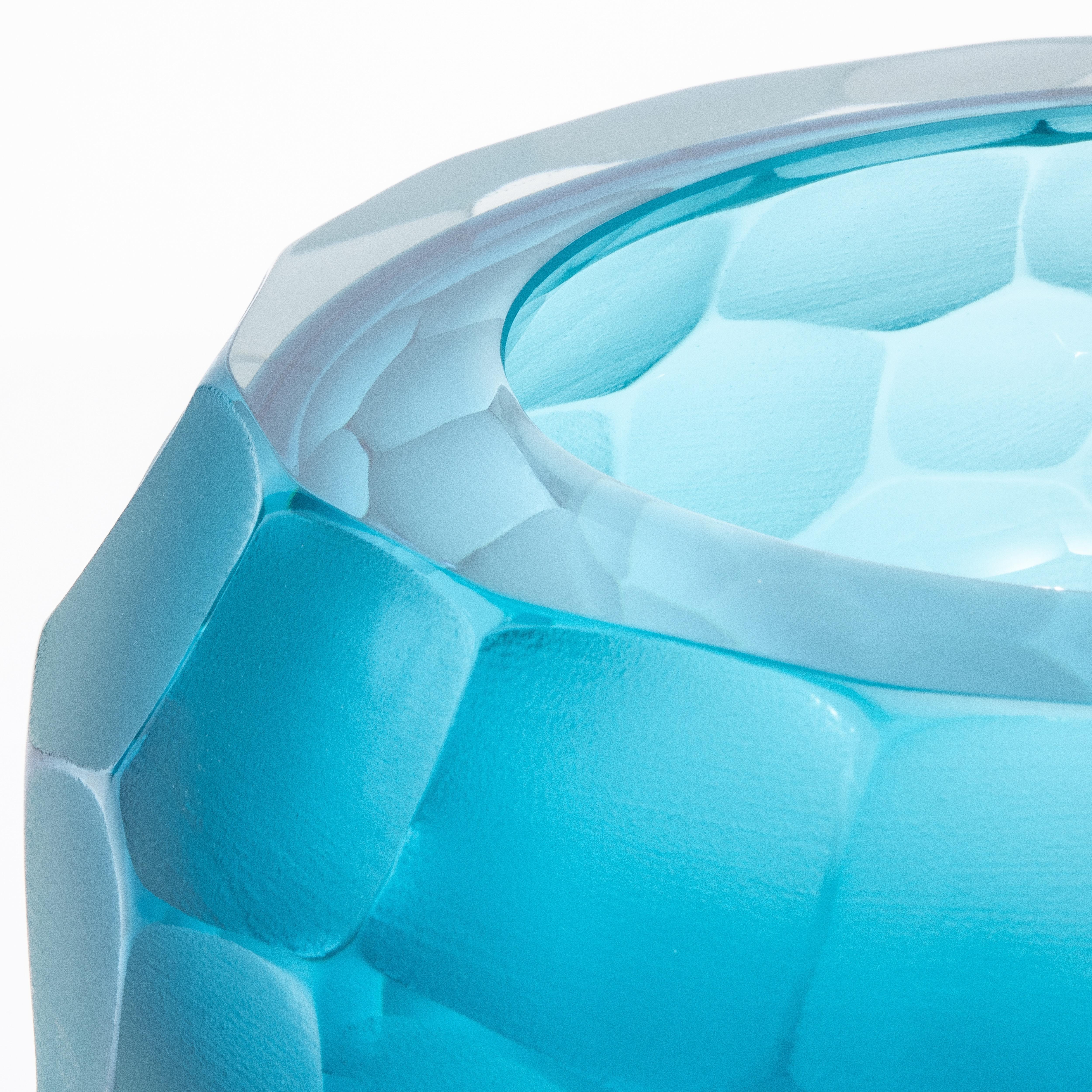 Questa ciotola di Murano soffiata a mano in acquamarina è un vero capolavoro dell'artigianato italiano, creato con la venerata tecnica del Battuto. La sua superficie meticolosamente scolpita presenta un motivo di sfaccettature irregolari, che evoca