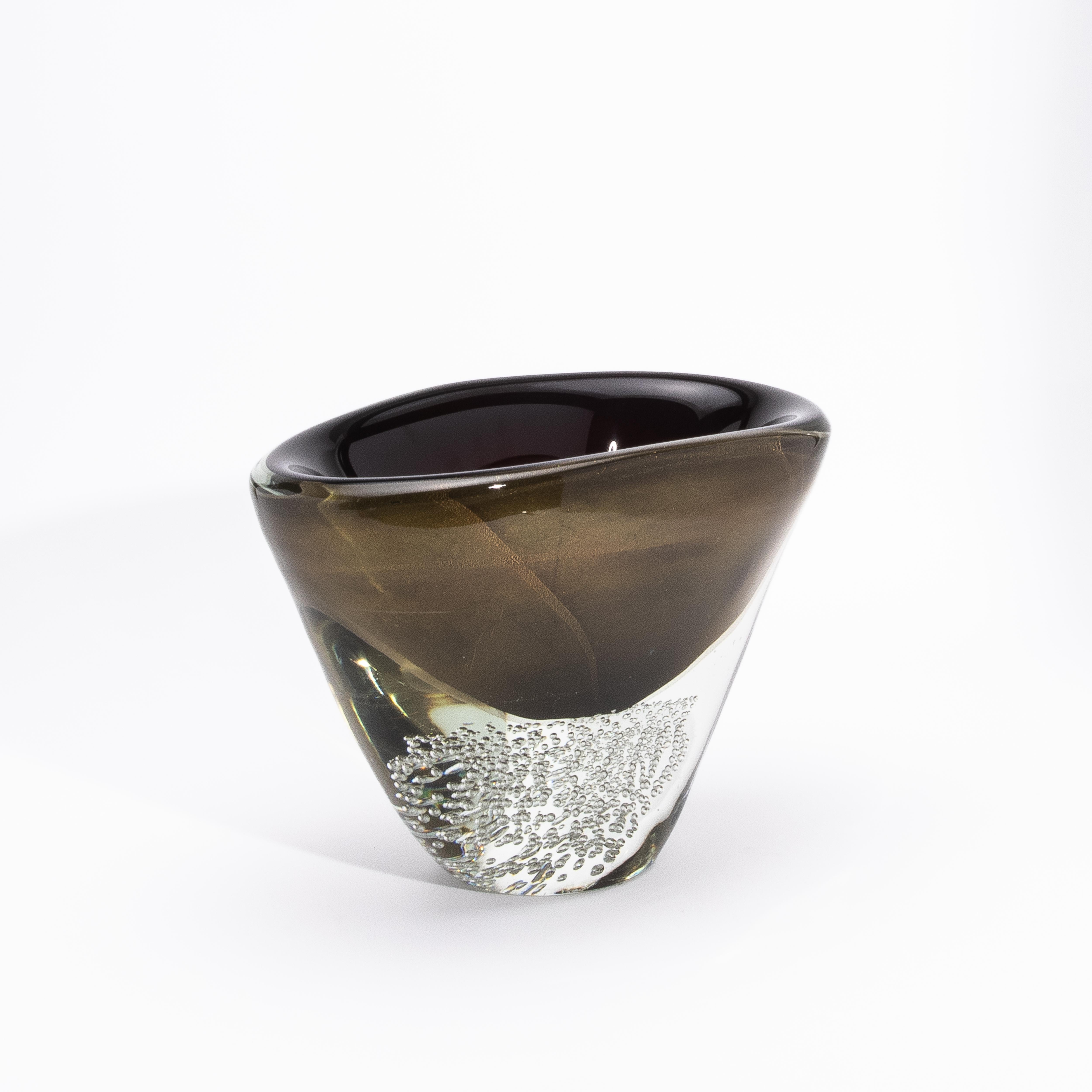 Die mundgeblasene moderne Murano-Schale in Schwarz/Klar mit 24-karätigen Goldflecken und -blasen ist ein meisterhafter Ausdruck italienischer Glaskunst, der kühne Kontraste mit raffinierter Opulenz verbindet. Der tiefschwarze Kern ist von einer