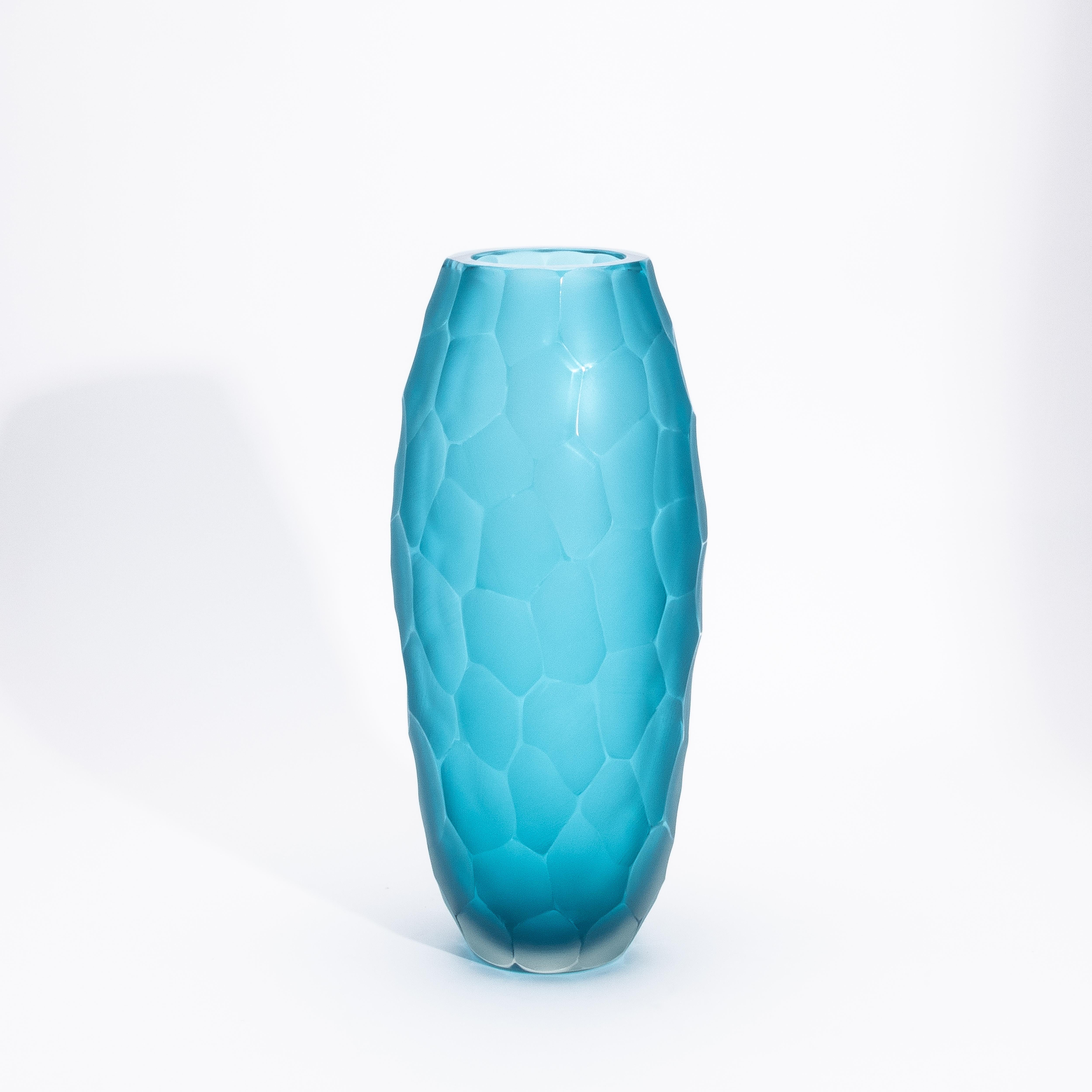 Il vaso alto moderno di Murano soffiato a mano in acquamarina media è un esempio straordinario di arte vetraria veneziana, magistralmente realizzata con la tecnica del Battuto. Questo intricato processo di intaglio a mano crea un'affascinante