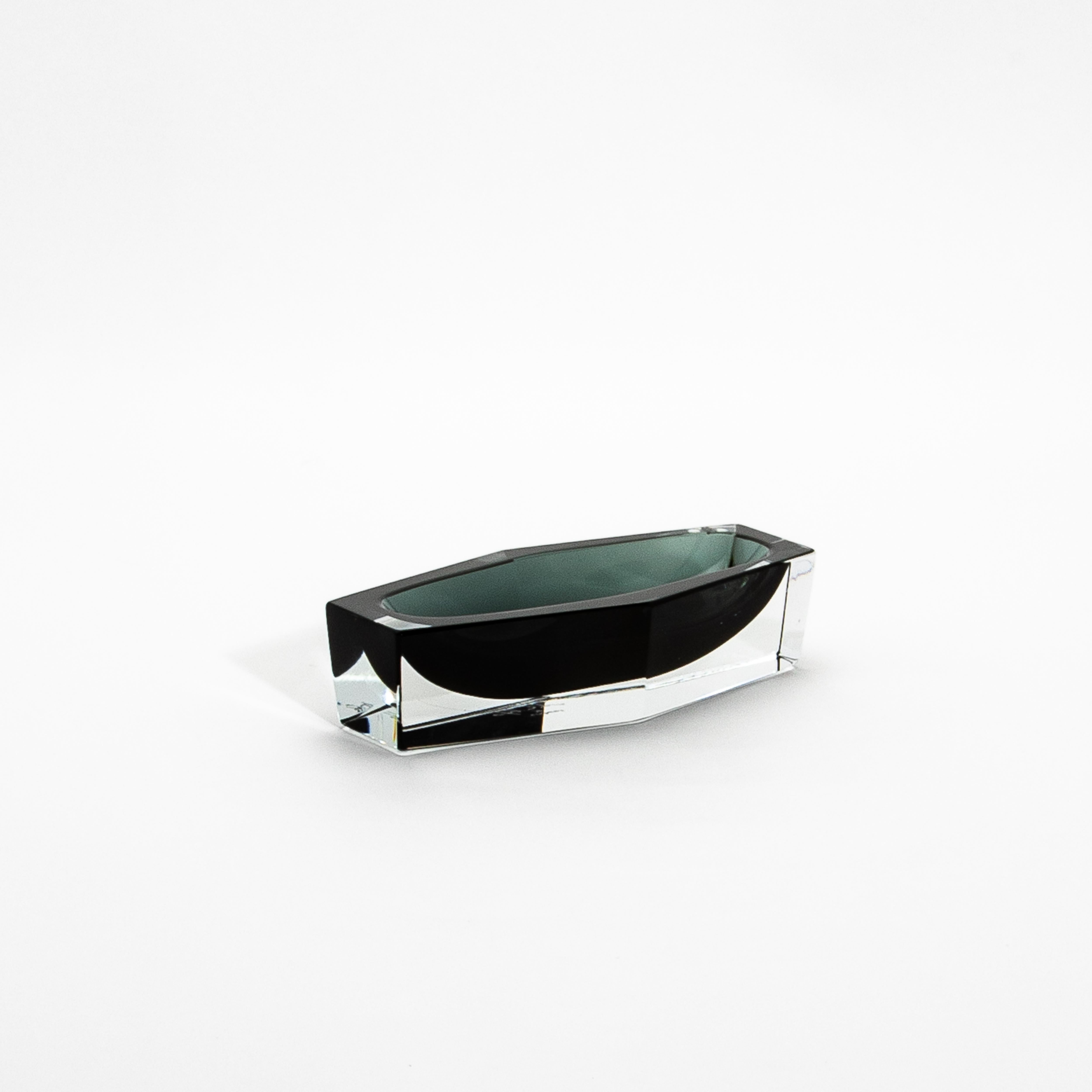 Dieser mundgeblasene graue Murano-Aschenbecher besticht durch sein minimalistisches Design und seine handwerkliche Raffinesse. Die delikate Balance zwischen dem glatten, transparenten Äußeren und dem rauchgrauen Kern erzeugt ein fesselndes Spiel von