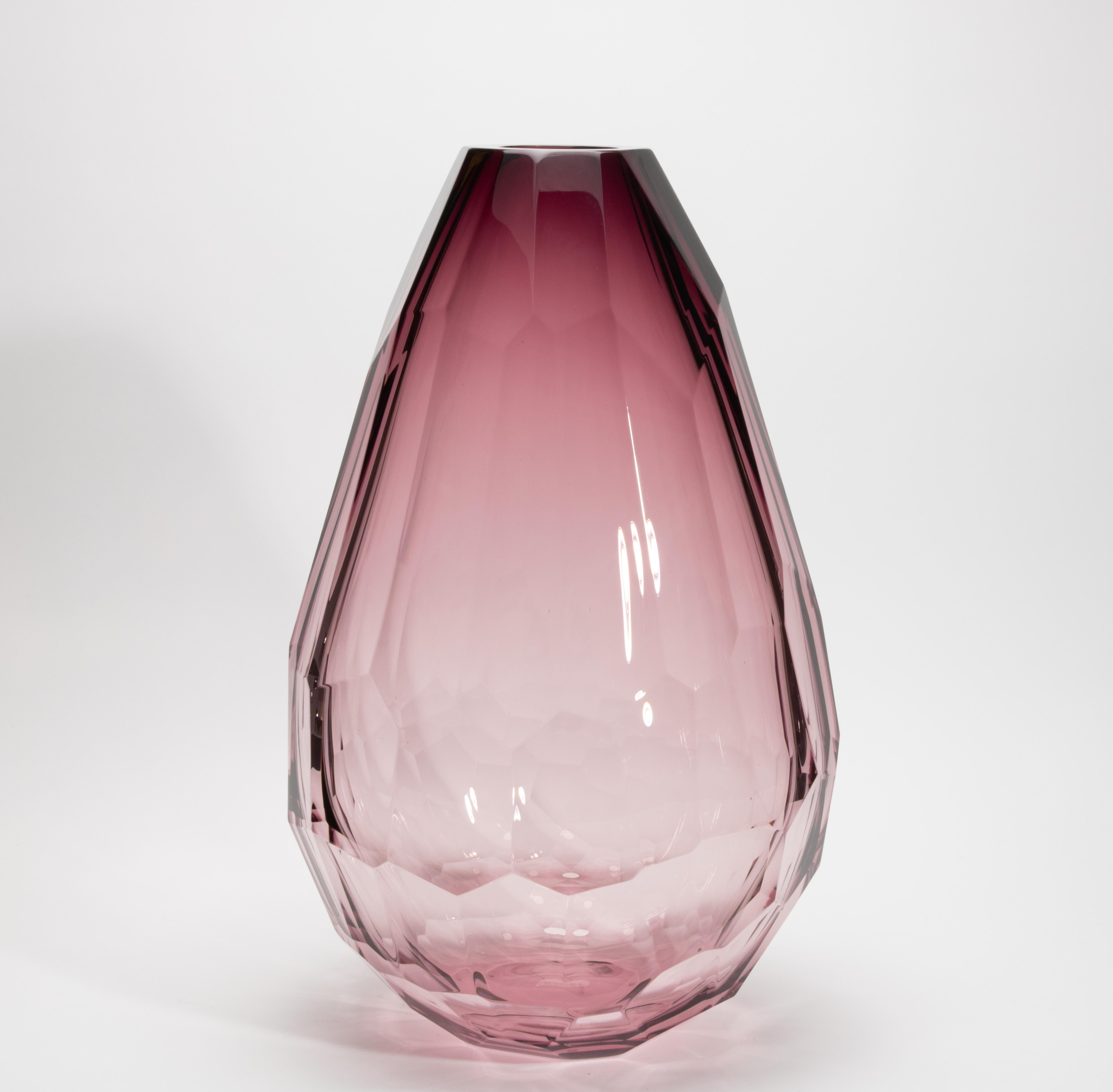 Un capolavoro di eleganza scultorea, questo vaso extra alto soffiato a mano di Murano in colore ametista affascina con la sua silhouette sfaccettata e la sua traslucenza eterea. Ogni superficie, tagliata con precisione geometrica, cattura e rifrange