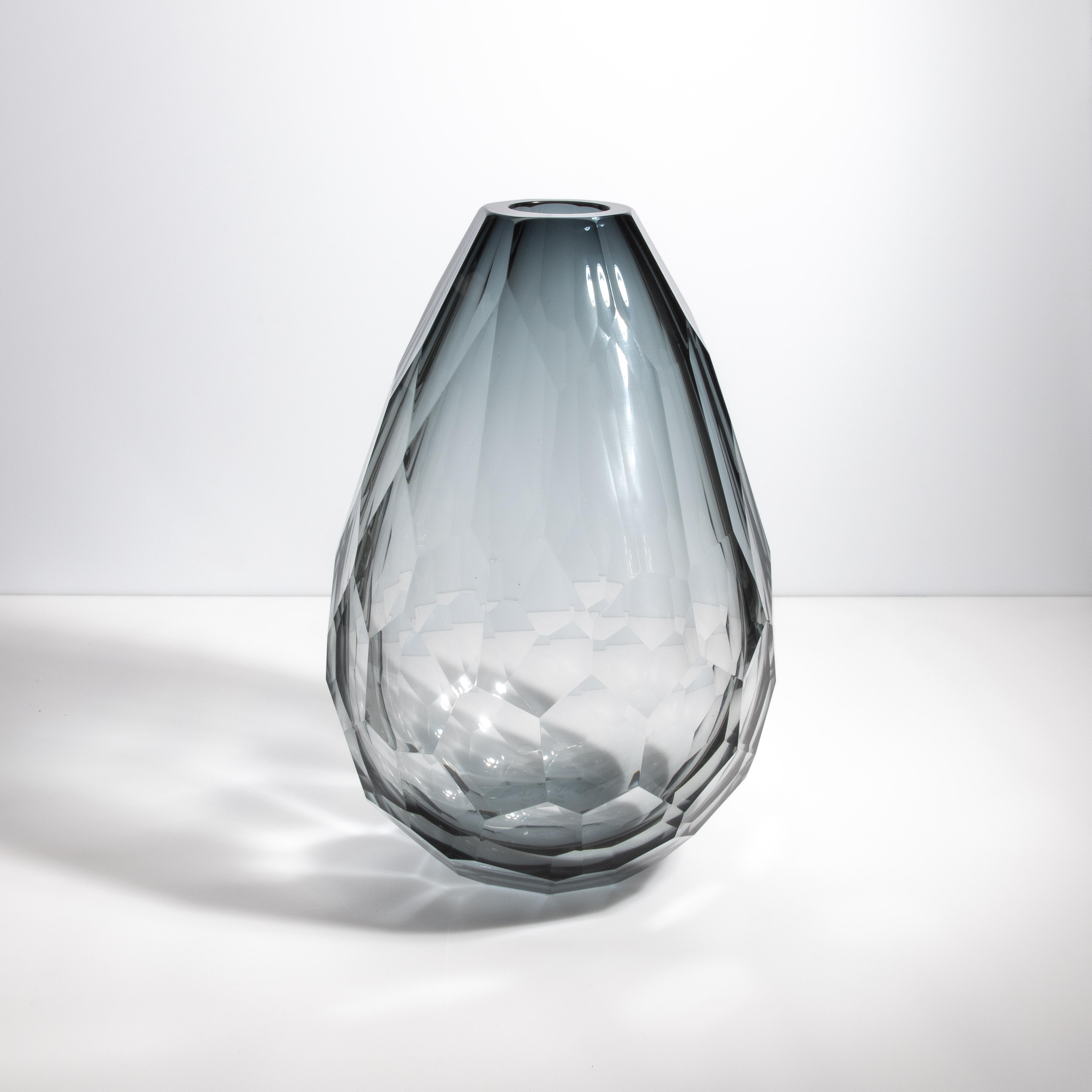 Questo vaso si distingue per la sua forma sostanziale e robusta, che emana un'aria di opulenza e grandezza. Il suo spessore non solo ne aumenta la durata, ma amplifica anche i giochi di luce sulla sua superficie sfaccettata, creando un effetto