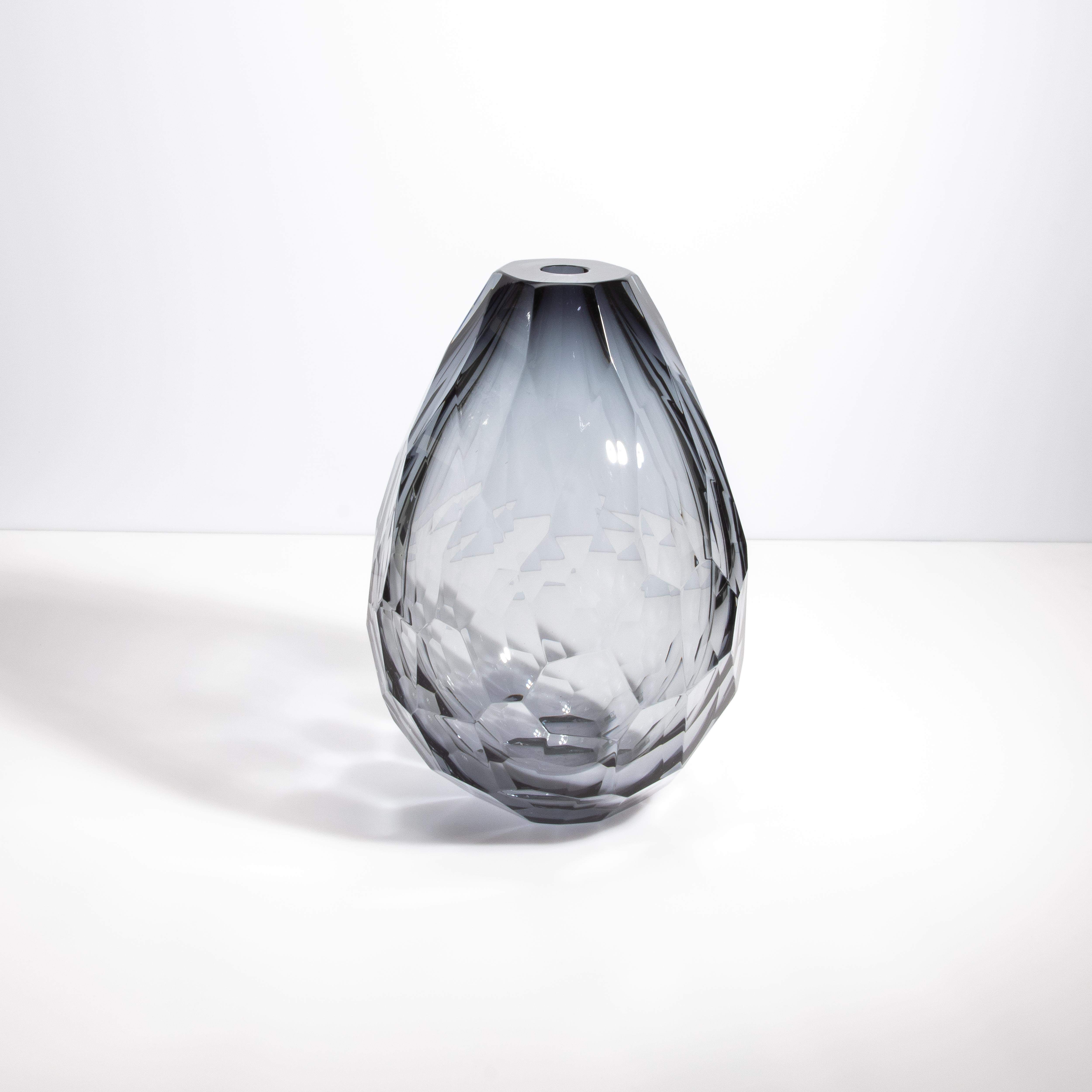 Questo vaso, creato nel cuore della tradizione vetraria di Murano, presenta un'eccezionale sfumatura grigia che conferisce un fascino sottile e raffinato al suo design geometrico. Ogni sfaccettatura è tagliata con precisione da esperti artigiani e