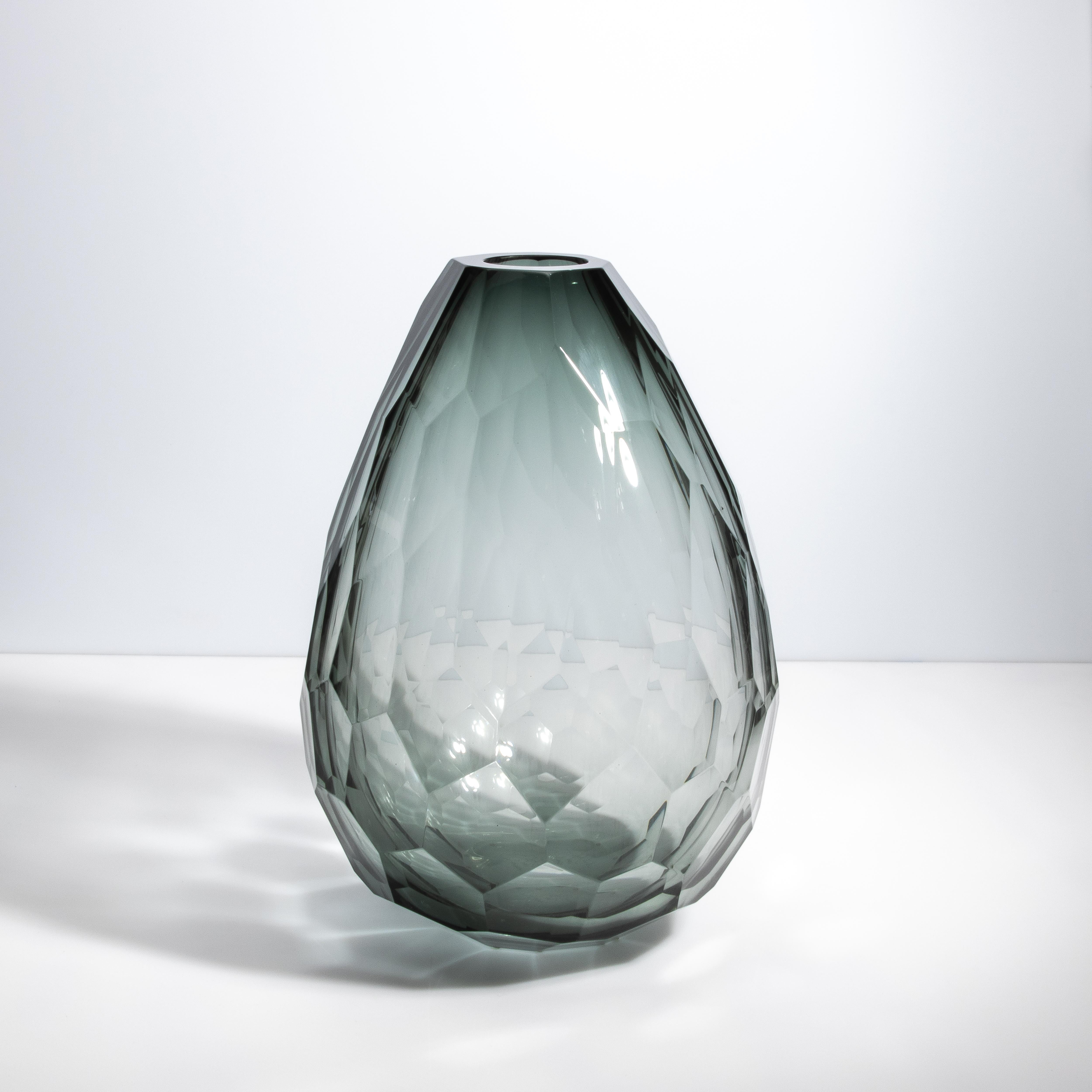 Questo vaso, creato nel cuore della tradizione vetraria di Murano, presenta un'eccezionale tonalità di tormalina che conferisce un fascino sottile e raffinato al suo design geometrico. Ogni sfaccettatura è tagliata con precisione da esperti