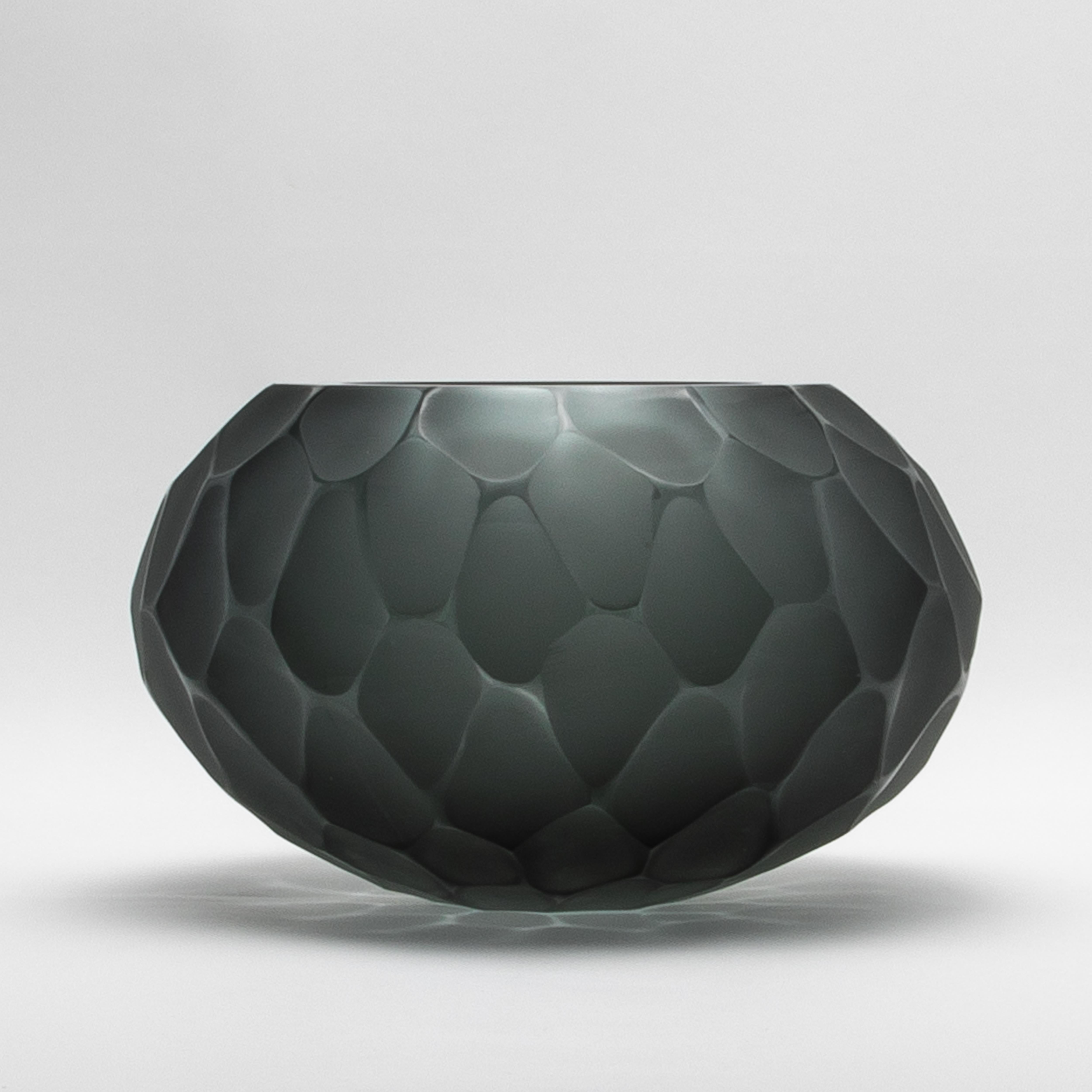 El Cuenco Battuto de Murano Soplado a Mano en Gris, tamaño grande, es una cautivadora obra de arte elaborada mediante la célebre técnica del battuto. Este meticuloso método de talla veneciana crea una superficie texturizada y facetada que imita el