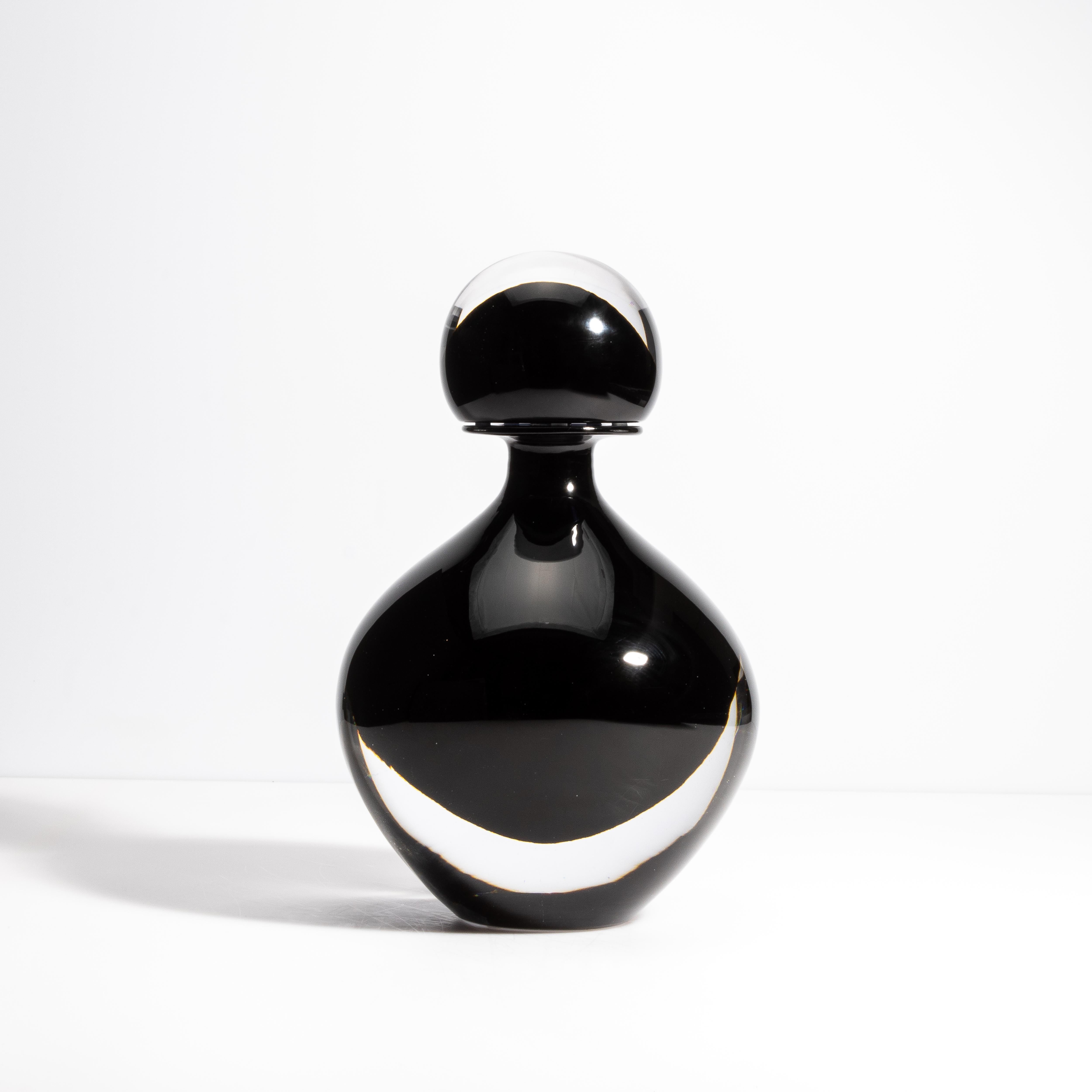 Lasciati conquistare dall'eleganza di questa bottiglia di Murano soffiata a mano, un vero capolavoro realizzato con il miglior vetro nero onice. La sua finitura lucida e la tonalità profonda e ricca trasudano raffinatezza, rendendolo un pezzo forte