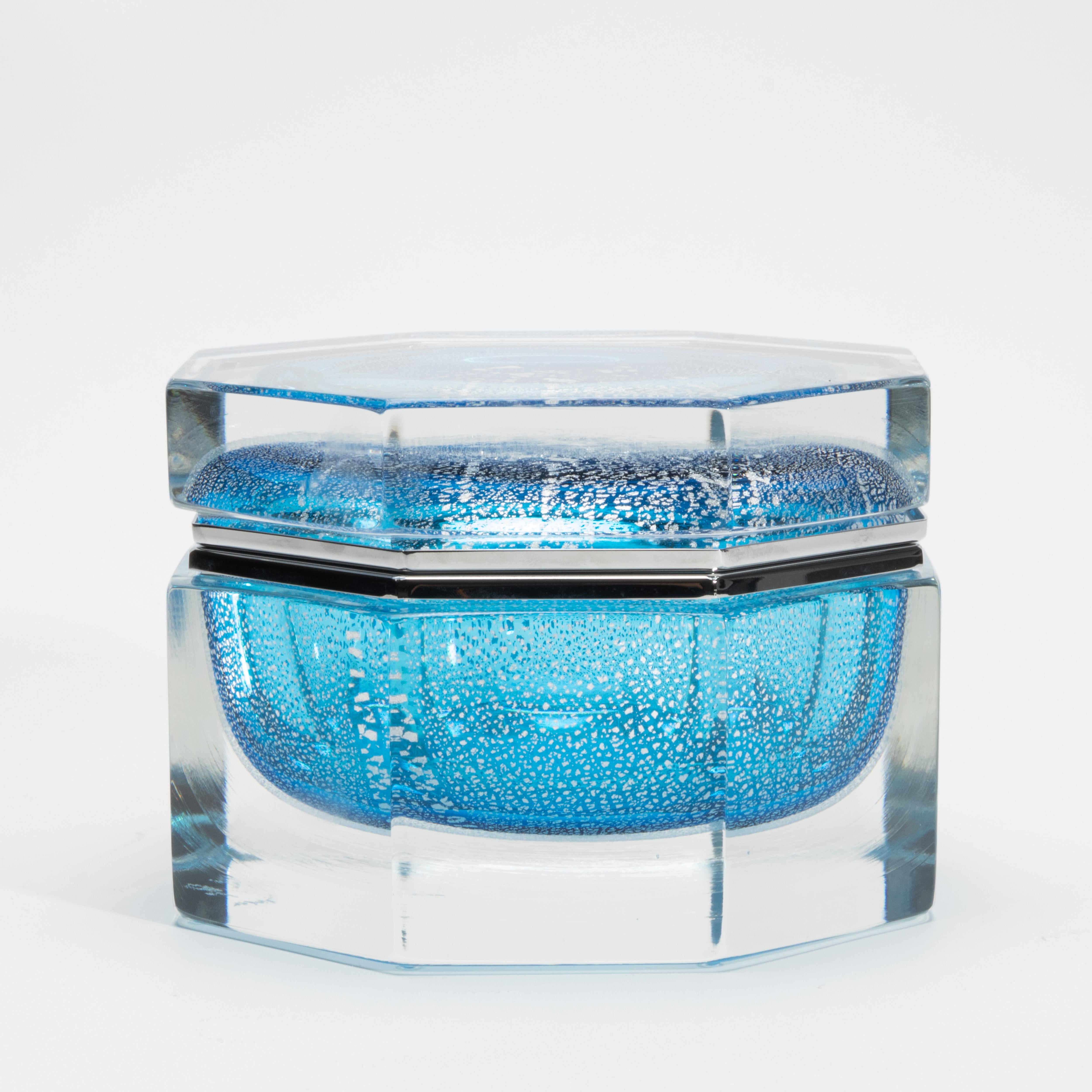 Hand-Blown Murano Box in Aqua Blue with Silver Flecks and Chrome Fittings captures the essence of Venetian artistry through an exquisite fusion of form, material, and luminosity. This sculptural treasure is hand-blown in Murano, Italy, where the