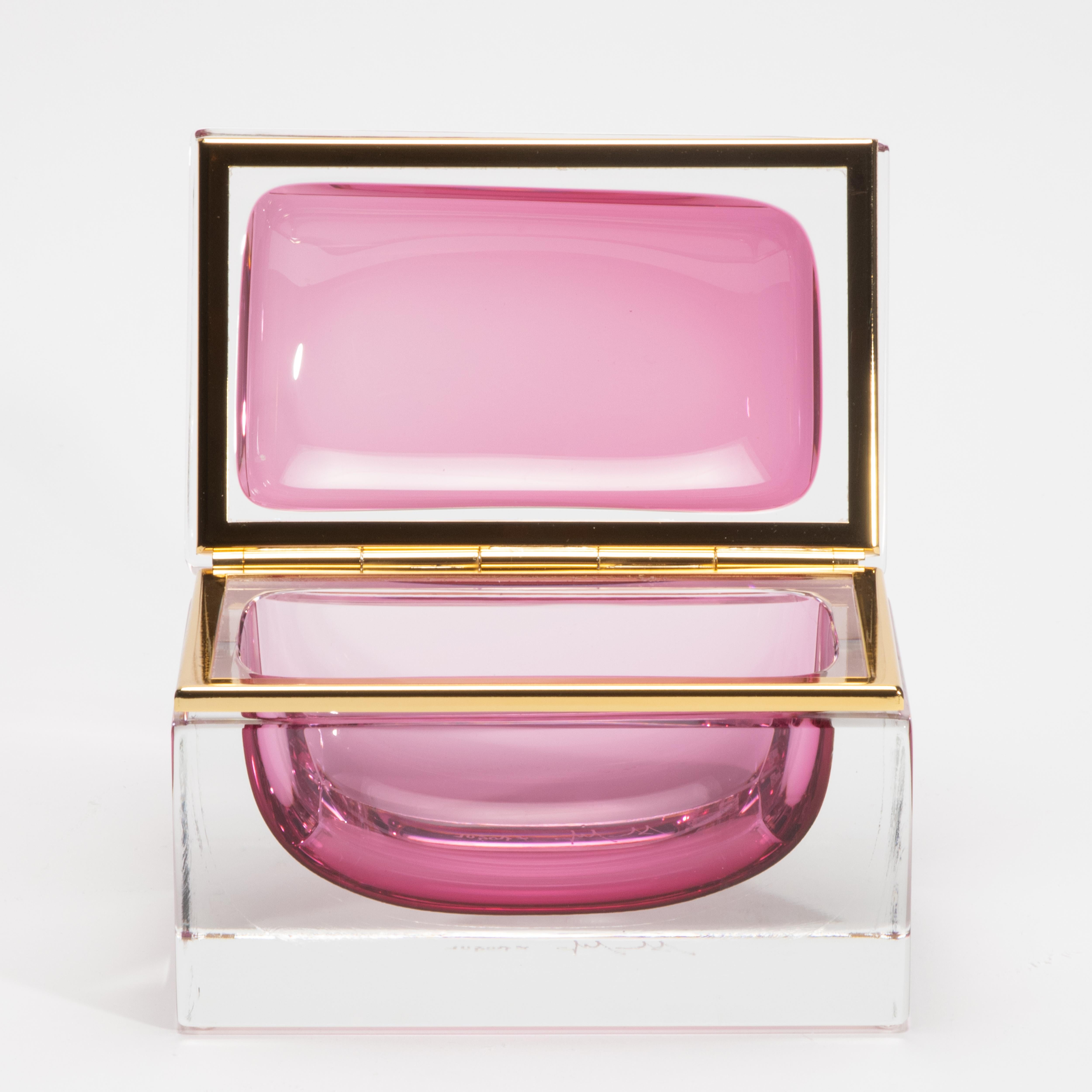 Hand-Blown Murano Box in Ruby with Brass Fittings is a radiant celebration of color, craftsmanship, and Italian elegance. Meticulously hand-blown in Murano, this striking piece showcases a lush ruby-toned glass core, suspended in a clear rectangular
