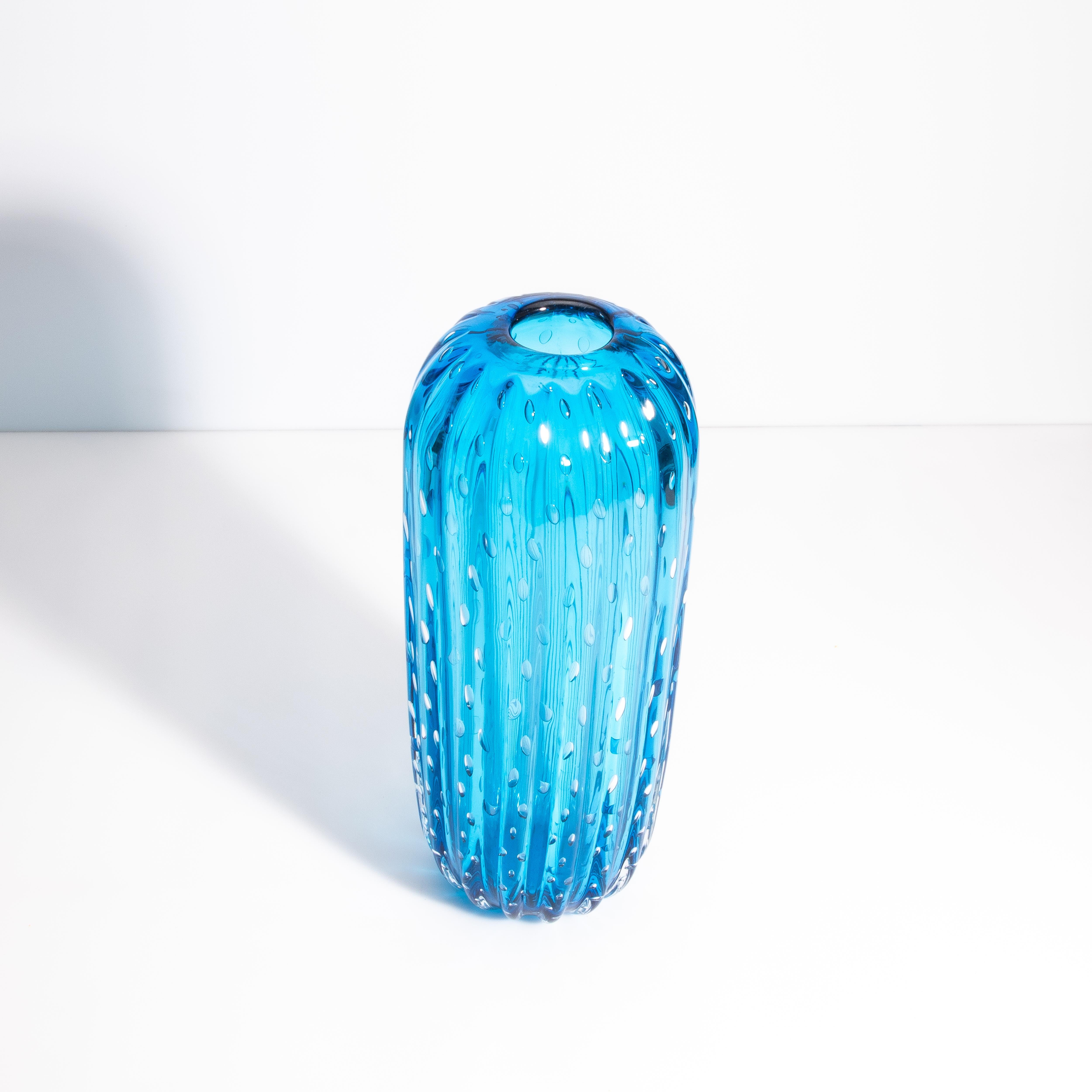Questo vaso alto ed elegante, disegnato con un'accattivante forma a cactus, incarna la squisita bellezza e l'impareggiabile maestria che ha reso il vetro di Murano un simbolo di lusso e raffinatezza per secoli.
Con una presenza regale, questo vaso