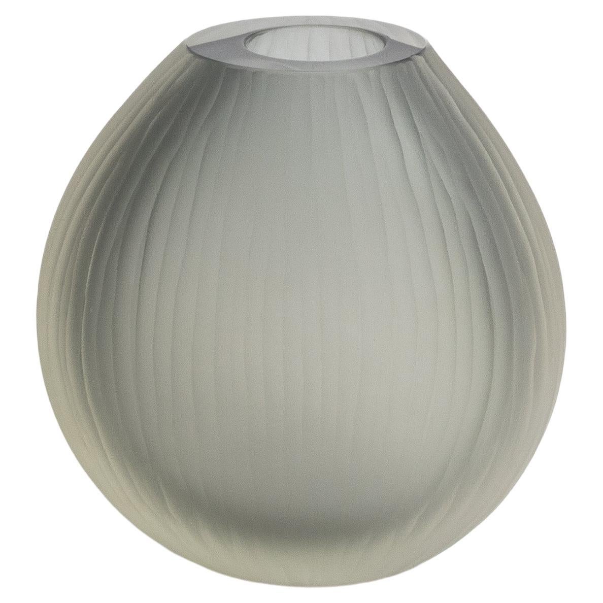 Ti presentiamo un capolavoro di arte vetraria che trascende la semplice decorazione, incarnando l'apice del lusso e della raffinatezza. Questo vaso soffiato a mano, con il suo fascino grigio fumo e la sua elegante struttura a coste, è una
