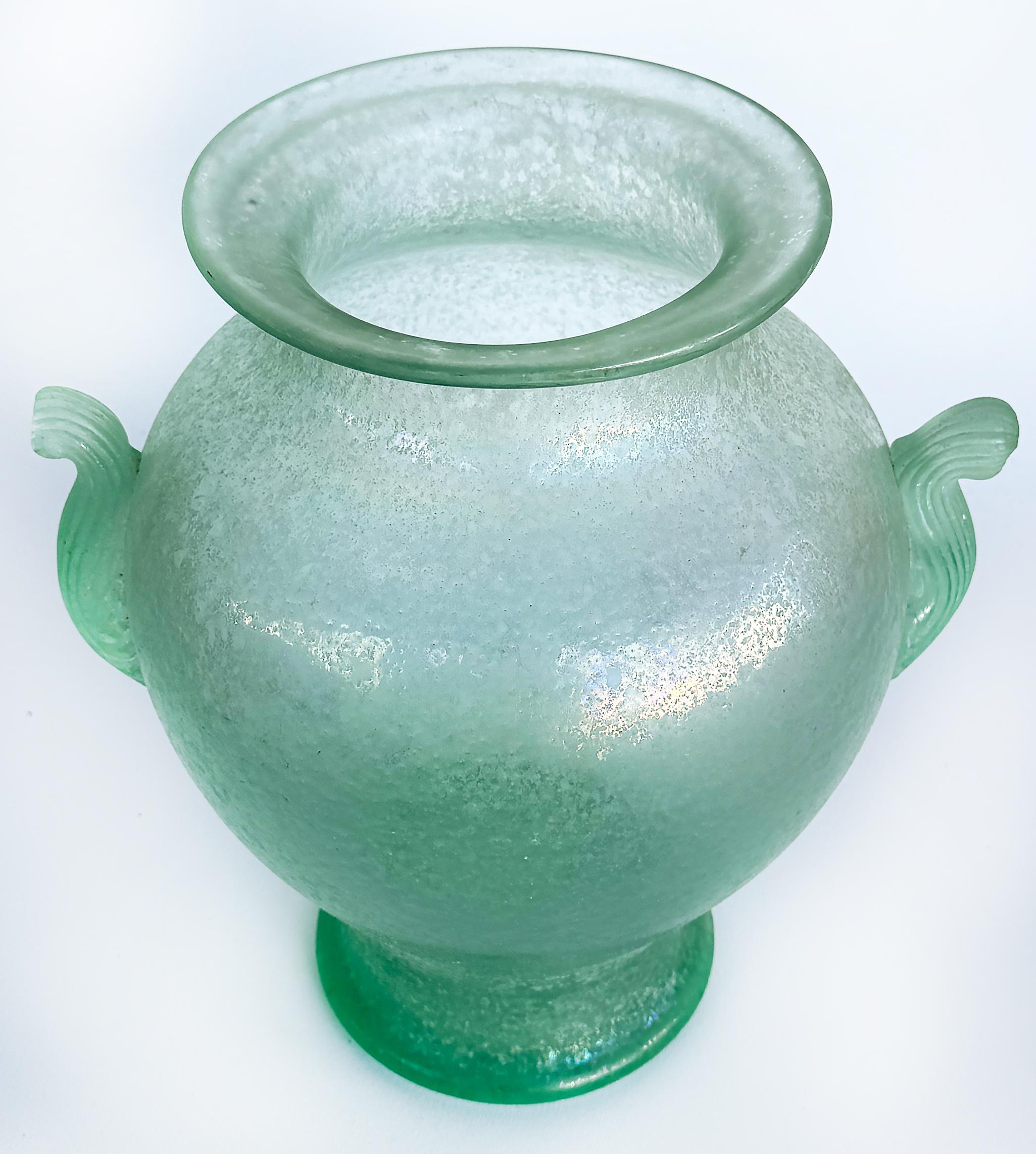 

Handgeblasene Murano Celadon venezianisches Scavo Glas Urnenvase, 2 Griffe

Zum Verkauf angeboten wird eine wunderbare Vase aus Murano-Glas aus den 1980er Jahren, die mit der Kunstfertigkeit der venezianischen Glasmacher in der Scavo-Technik