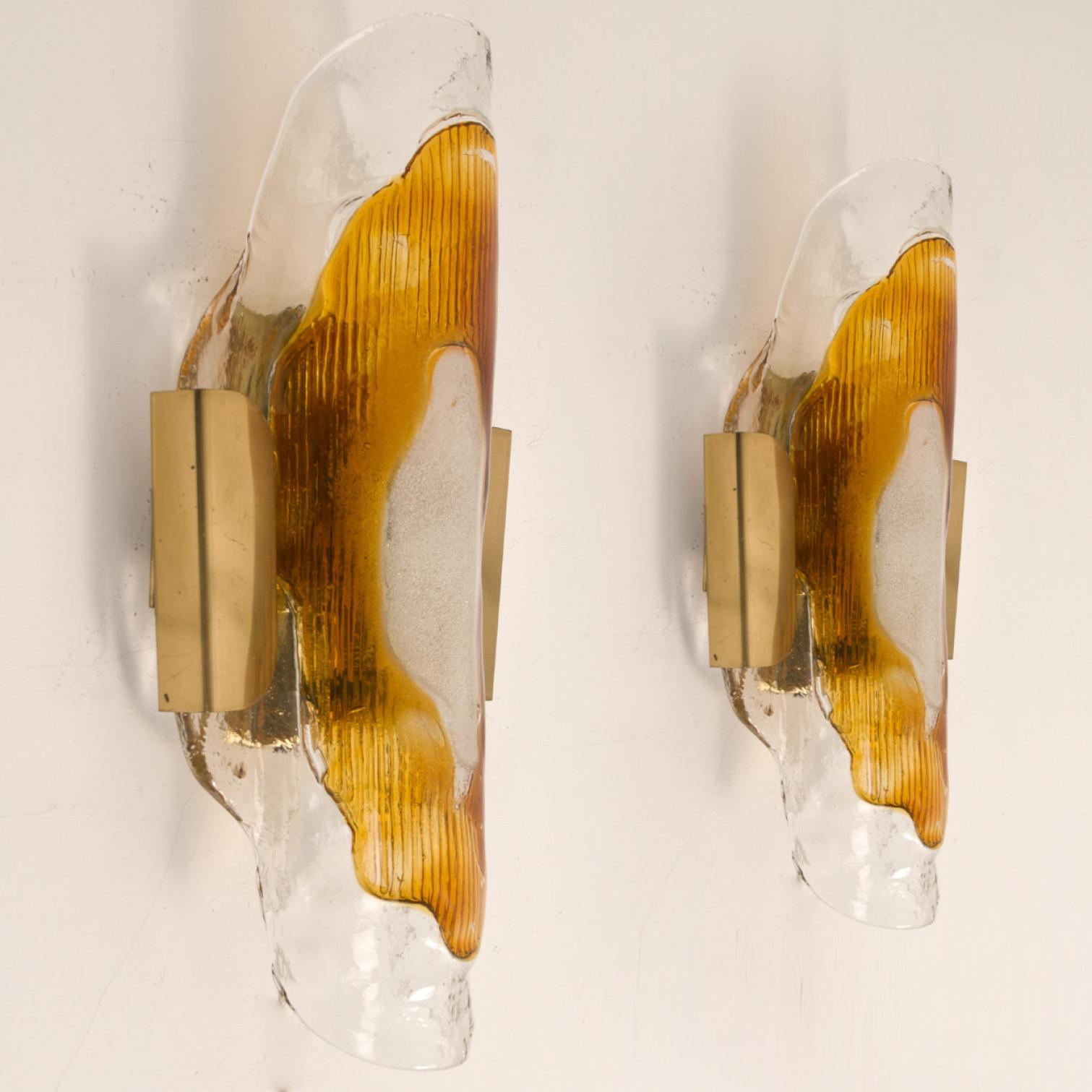 One of three beautiful wall lights, manufactured in the Mid Century, circa 1970 (end of 1960s and beginning of 1970s).
A brass frame and a bi-colored (clear and orange) hand blown Murano glass. Each piece of glass meticulously hand formed in clear