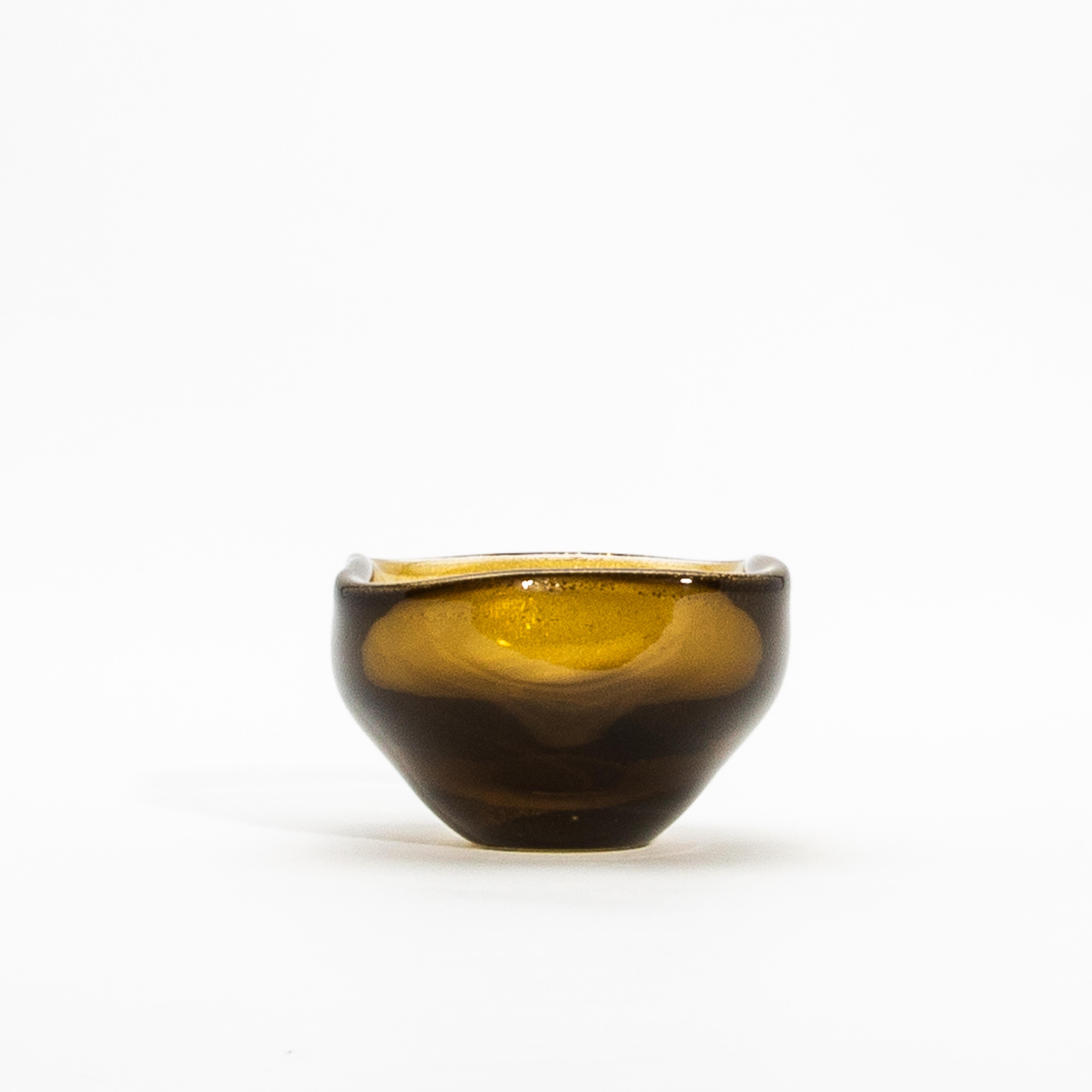 Radiating elegance, this hand-blown Murano dish in a warm tobacco hue is a celebration of Venetian glassmaking heritage. Adorned with shimmering 24-karat gold flecks, its design exudes opulence, while the undulating edges add a soft, organic touch