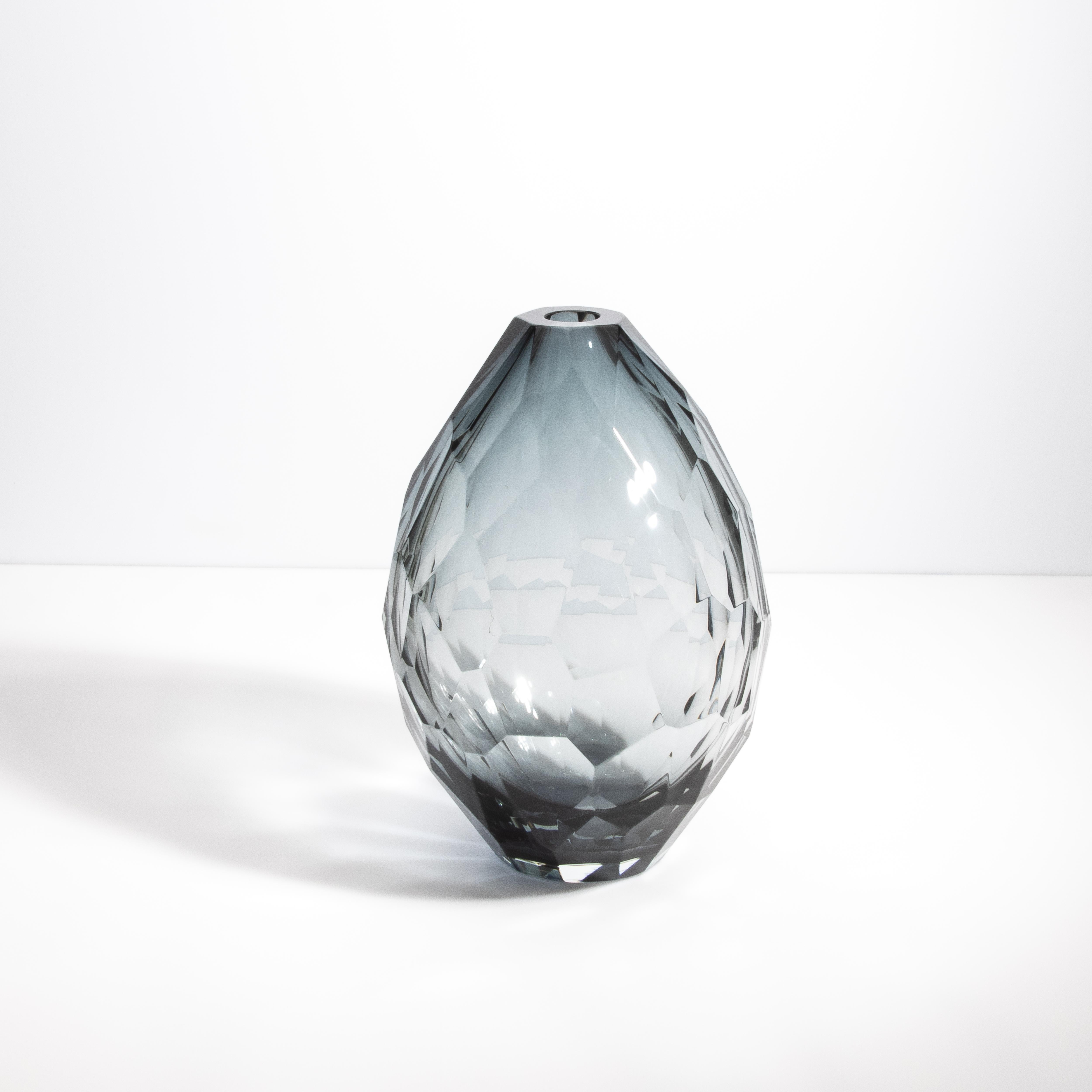 Questo vaso, creato nel cuore della tradizione vetraria di Murano, presenta un'eccezionale sfumatura grigia che conferisce un fascino sottile e raffinato al suo design geometrico. Ogni sfaccettatura è tagliata con precisione da esperti artigiani e