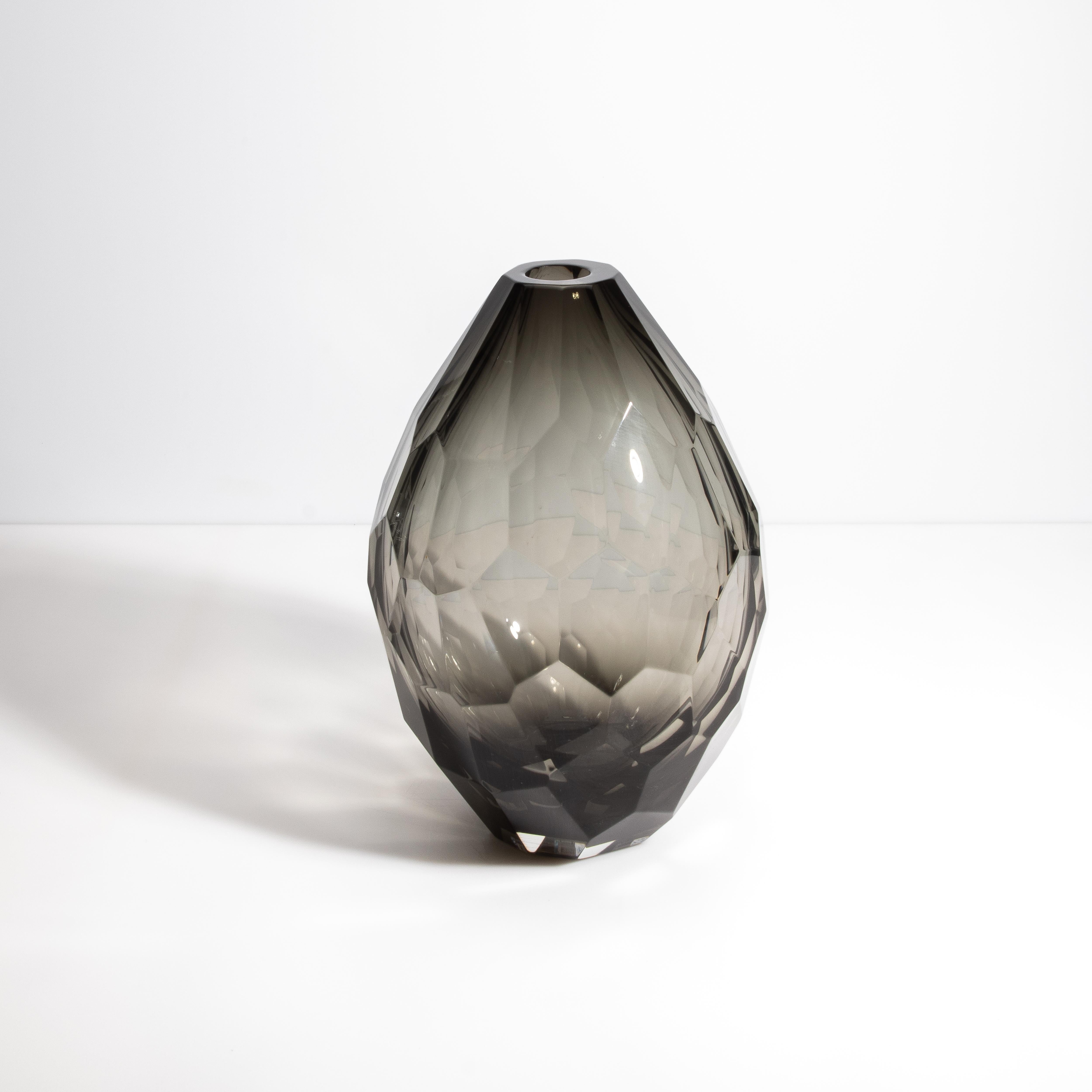 Ce vase dégage un air d'élégance raffinée, capturant la beauté intemporelle du verre de Murano. Sa teinte fumée sophistiquée s'harmonise parfaitement avec le design facetté du vase, créant un jeu d'ombre et de lumière fascinant. Chaque angle du vase