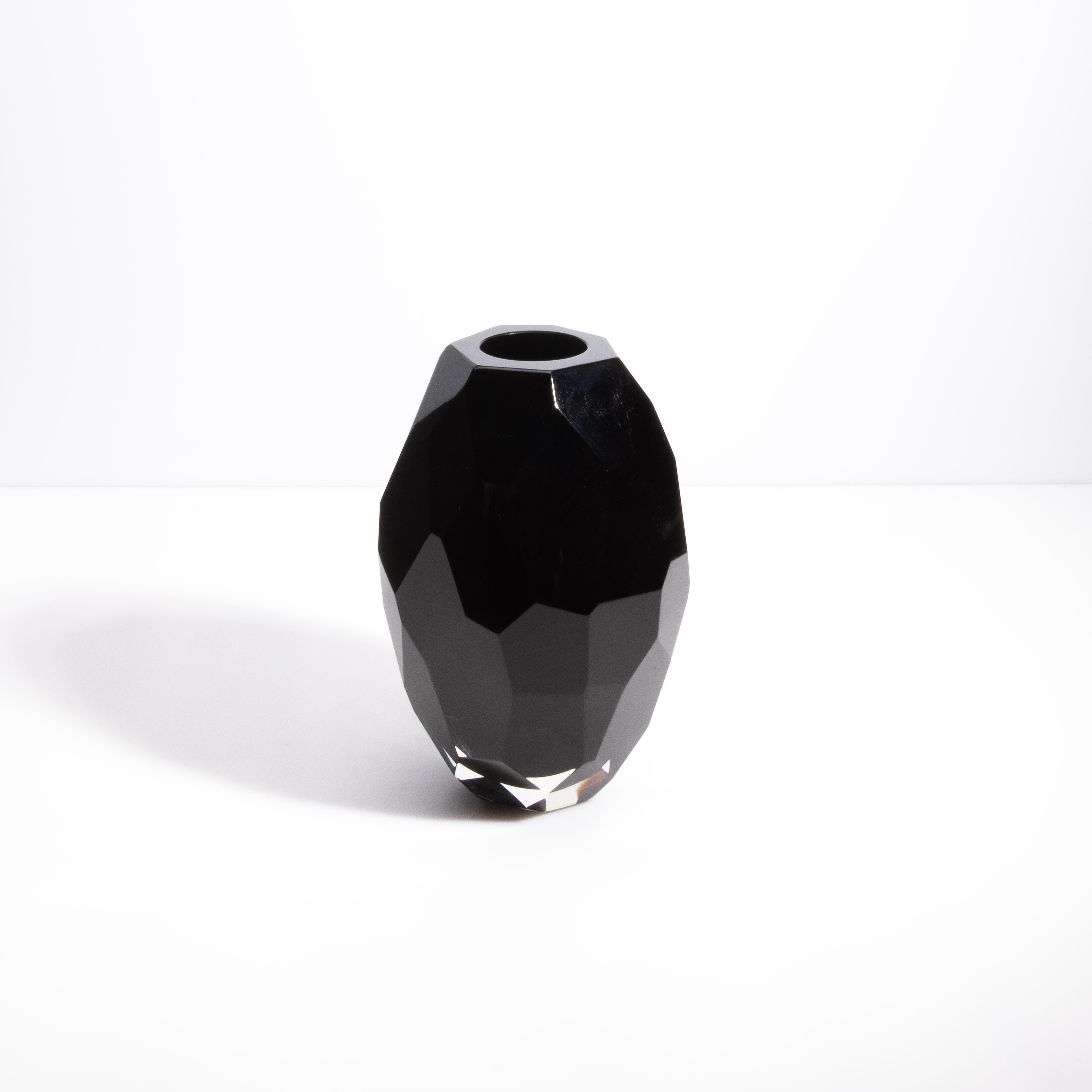 Drawing upon the profound elegance of Italian design, this black facet vase is a masterful creation of Murano artisans. Its deep, onyx black glass is meticulously hand-cut into geometric facets, each angle capturing and refracting light in a dance