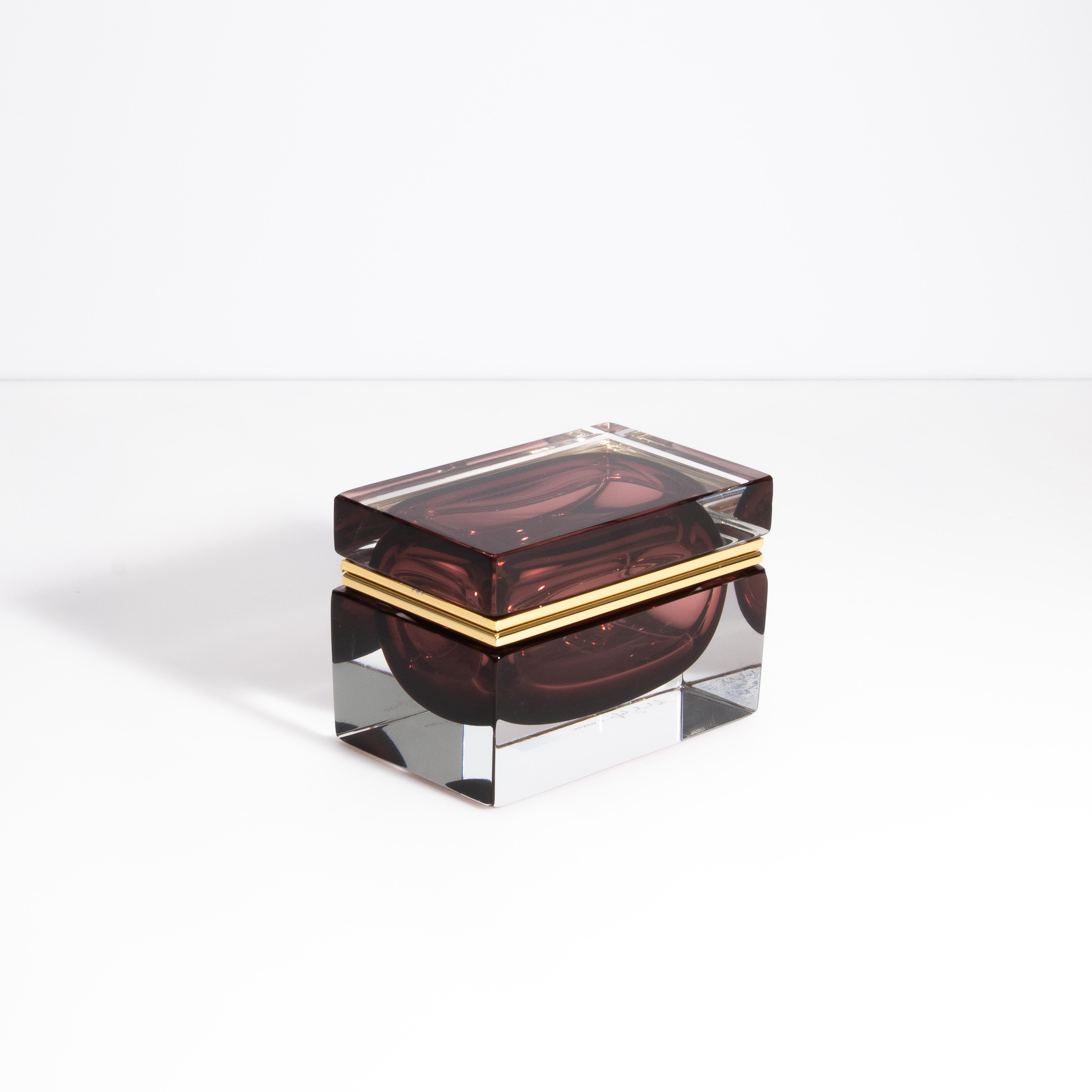 This evocative and alluring Murano glass box is a magnificent fusion of masterful craftsmanship and natural beauty. Handcrafted on the famed Venetian island of Murano, this box showcases the mesmerizing allure of amethyst, a gemstone revered for its