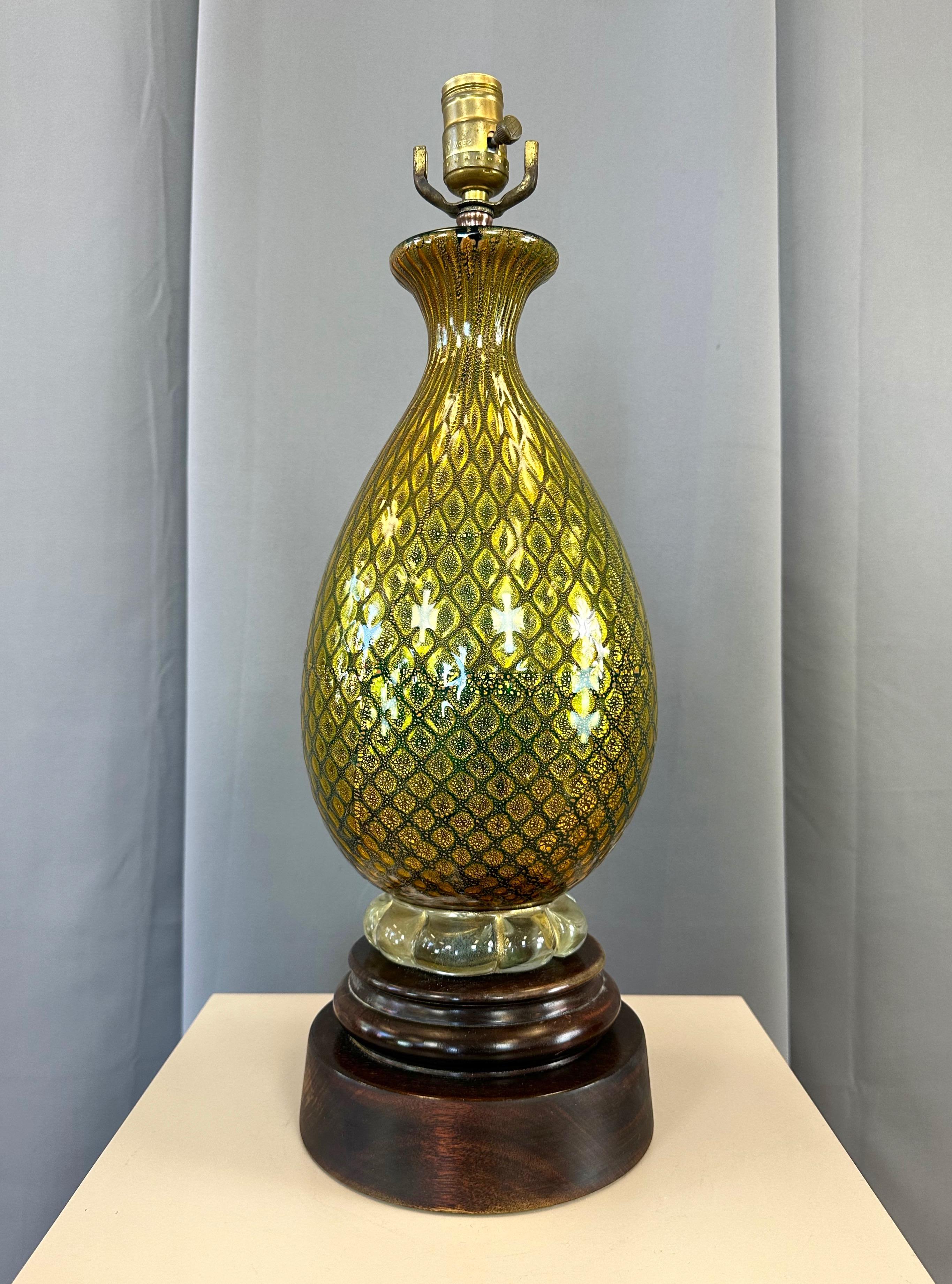 An absolutely stunning and very uncommon 1940s Italian Murano hand-blown green glass table lamp with gold leaf accents on a turned wood mahogany base.

Inverted balloon-shaped body presents from a distance as olive green, and features a shimmering