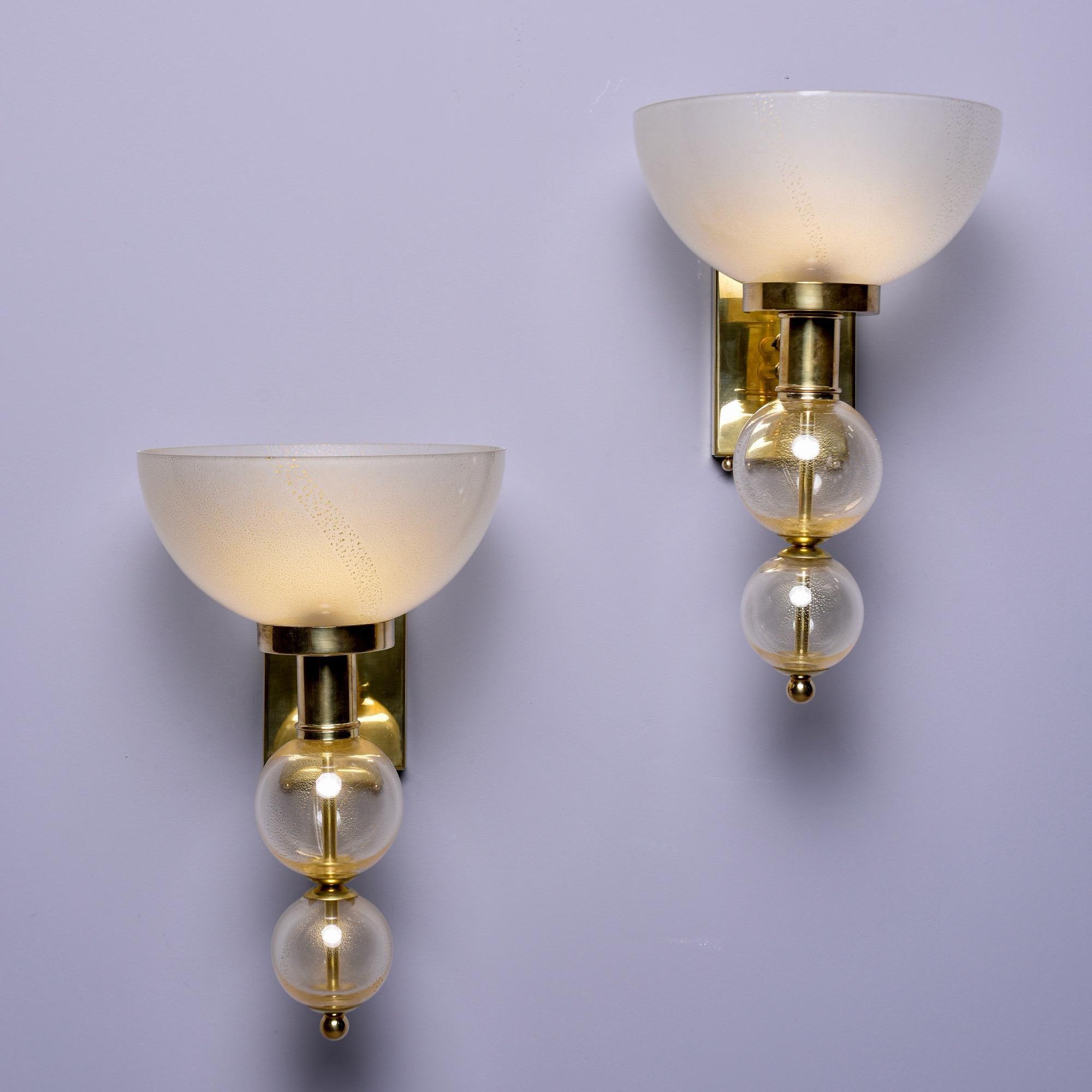 New and made in Italy, this pair of sconces features a rectangular polished brass back plate with gold flecked Murano glass globes and round finials. Sold and priced as a pair.