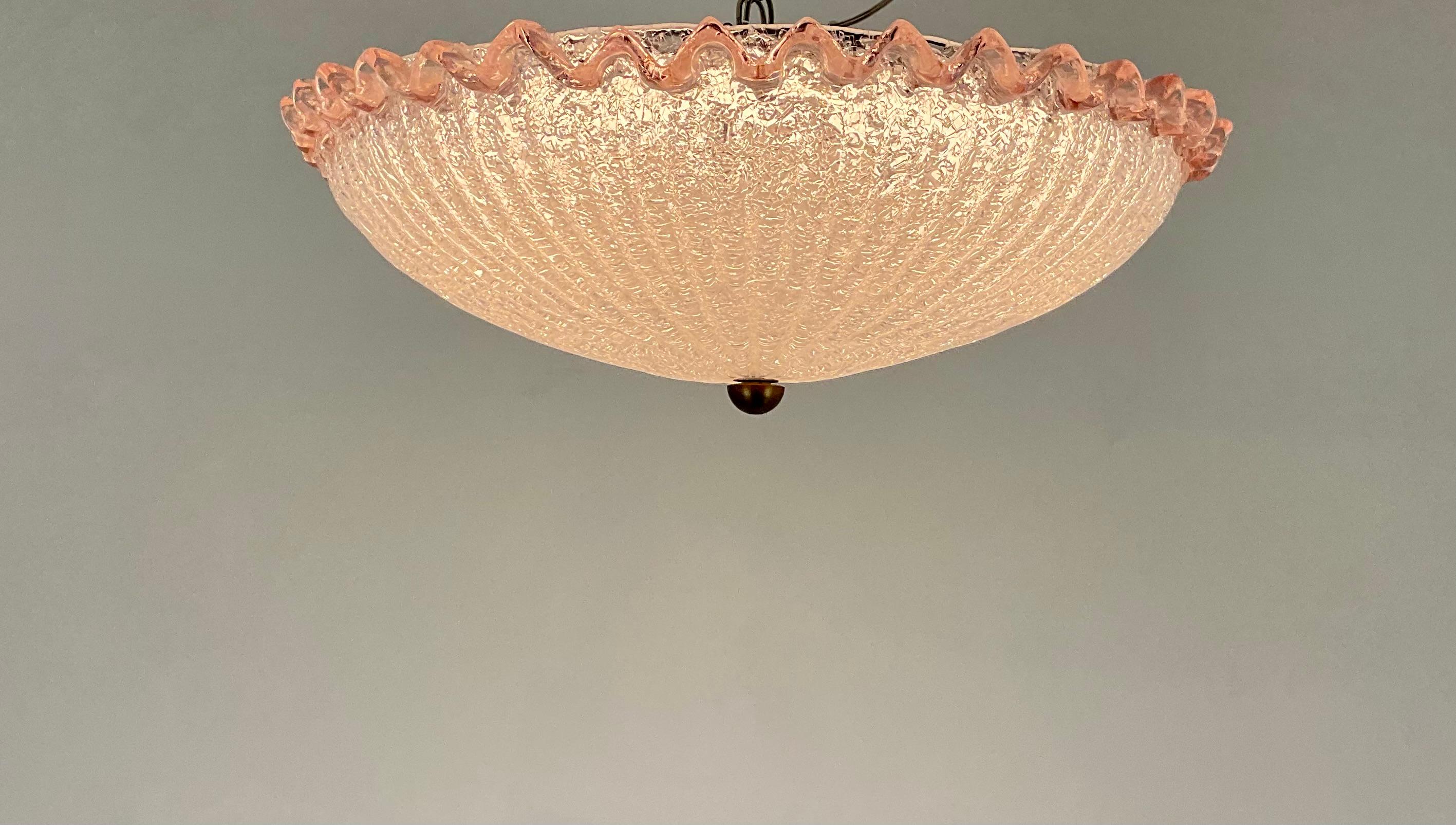 Magnifique luminaire semi-affleurant en verre italien soufflé à la main. Bol en verre salé côtelé avec une élégante bordure à volants rose pâle. Complément spectaculaire à toute pièce.

Il en existe un deuxième identique, dont le prix est indiqué
