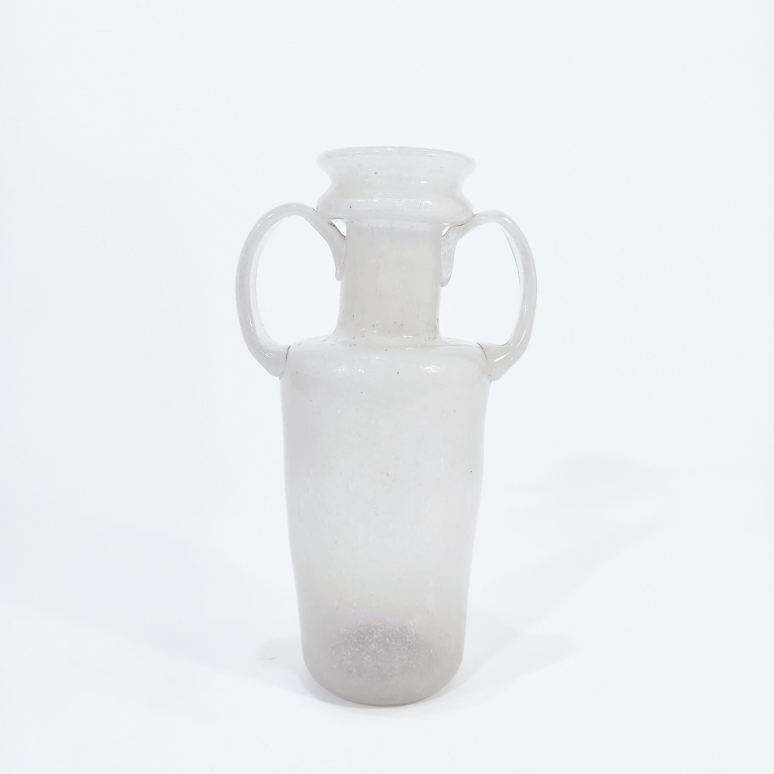 Murano glass vase attributed to Flavio Poli and produced by Seguso Vetri d'Arte in the 40s. Milky glass body with bubbles and subtly irregular and asymmetrical shape like an amphora with two handles.
The technique of the pulegoso glass is carried