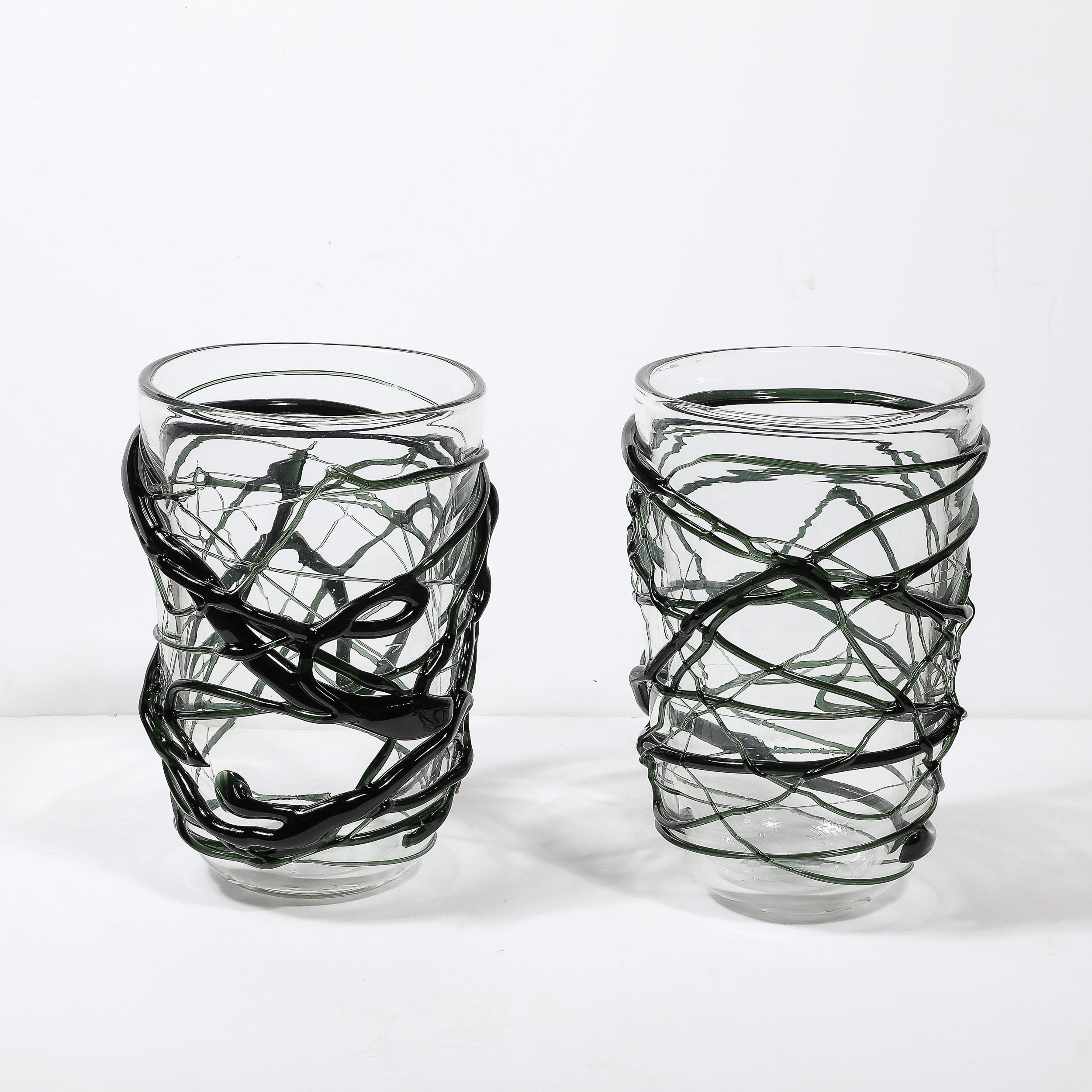 Este llamativo par de jarrones de cristal de Murano soplado a mano presenta esculturales estrías orgánicas en un vibrante verde viridiana, que muestran el arte y la tradición de la cristalería veneciana. Cada jarrón está meticulosamente elaborado,