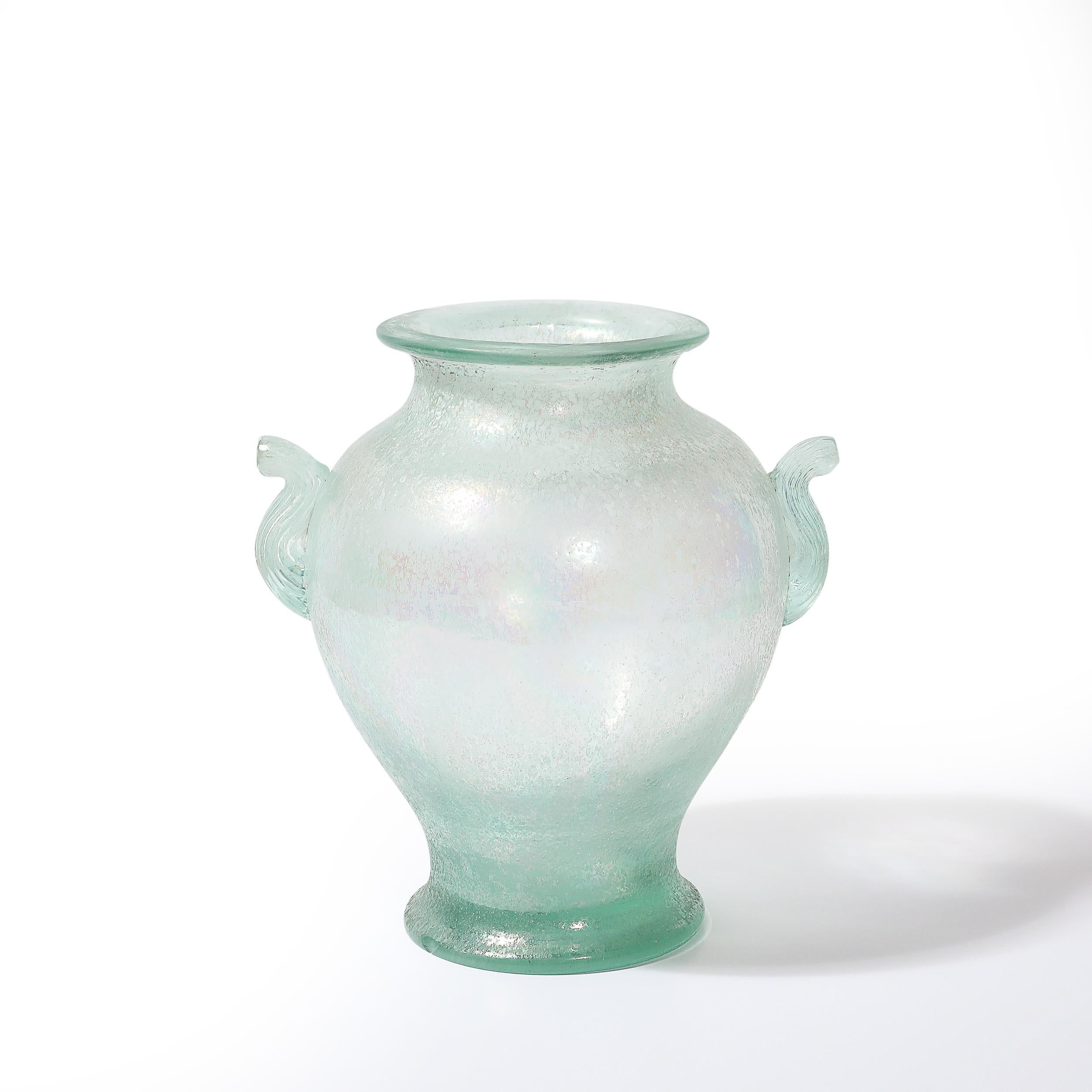 Diese außergewöhnliche Vase mit zwei Henkeln aus Murano, die um 1980 in Italien mundgeblasen wurde, ist ein Beispiel für die hohe Kunstfertigkeit der venezianischen Glasmacher. Die mit der Scavo-Technik gefertigte Vase besticht durch ihr