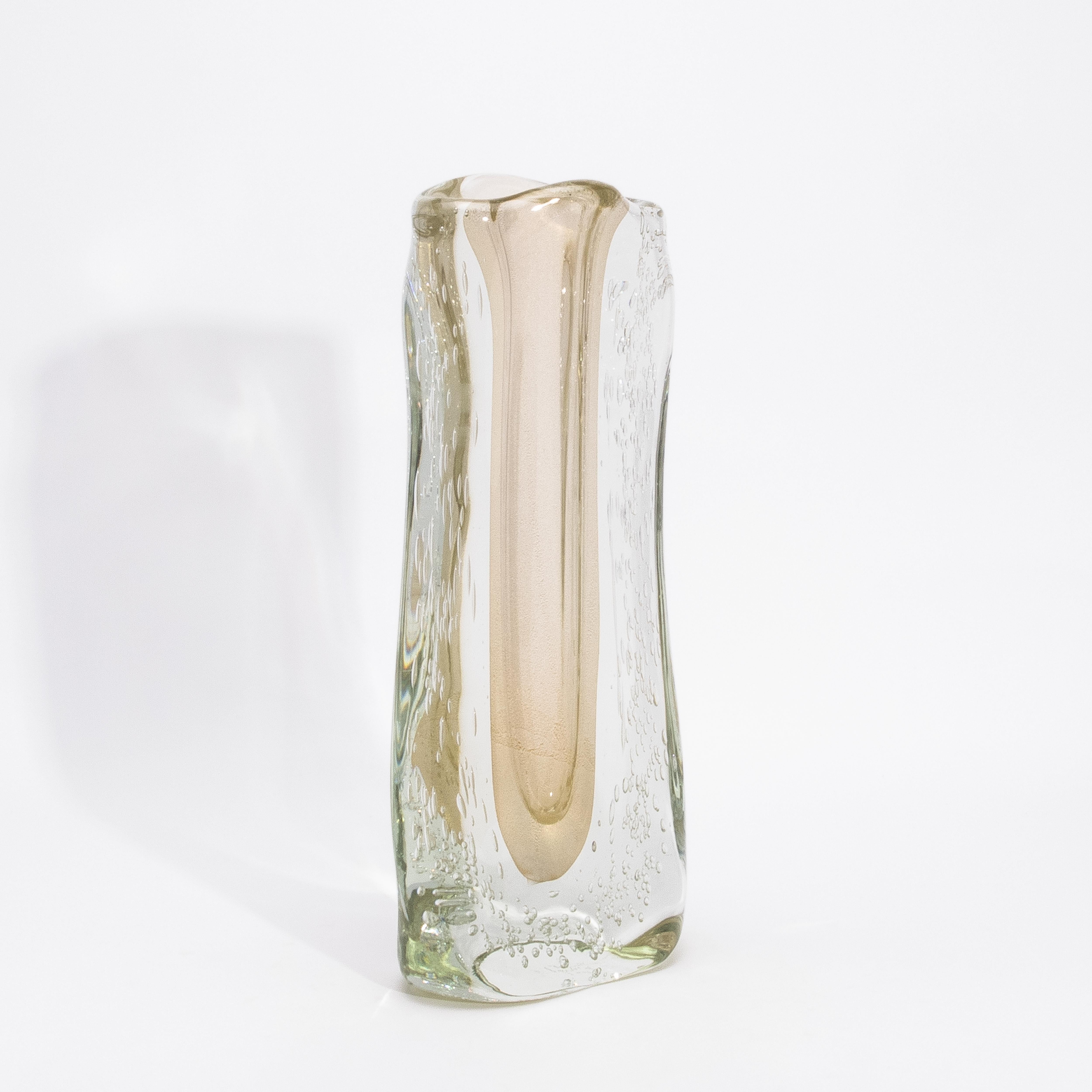 Incarnazione luminosa dell'arte del vetro di Murano, questo vaso fluido moderno di Murano soffiato a mano, trasparente con macchie e bolle d'oro a 24 carati, evoca un'eleganza senza tempo nella sua forma più raffinata. La morbida tonalità champagne,