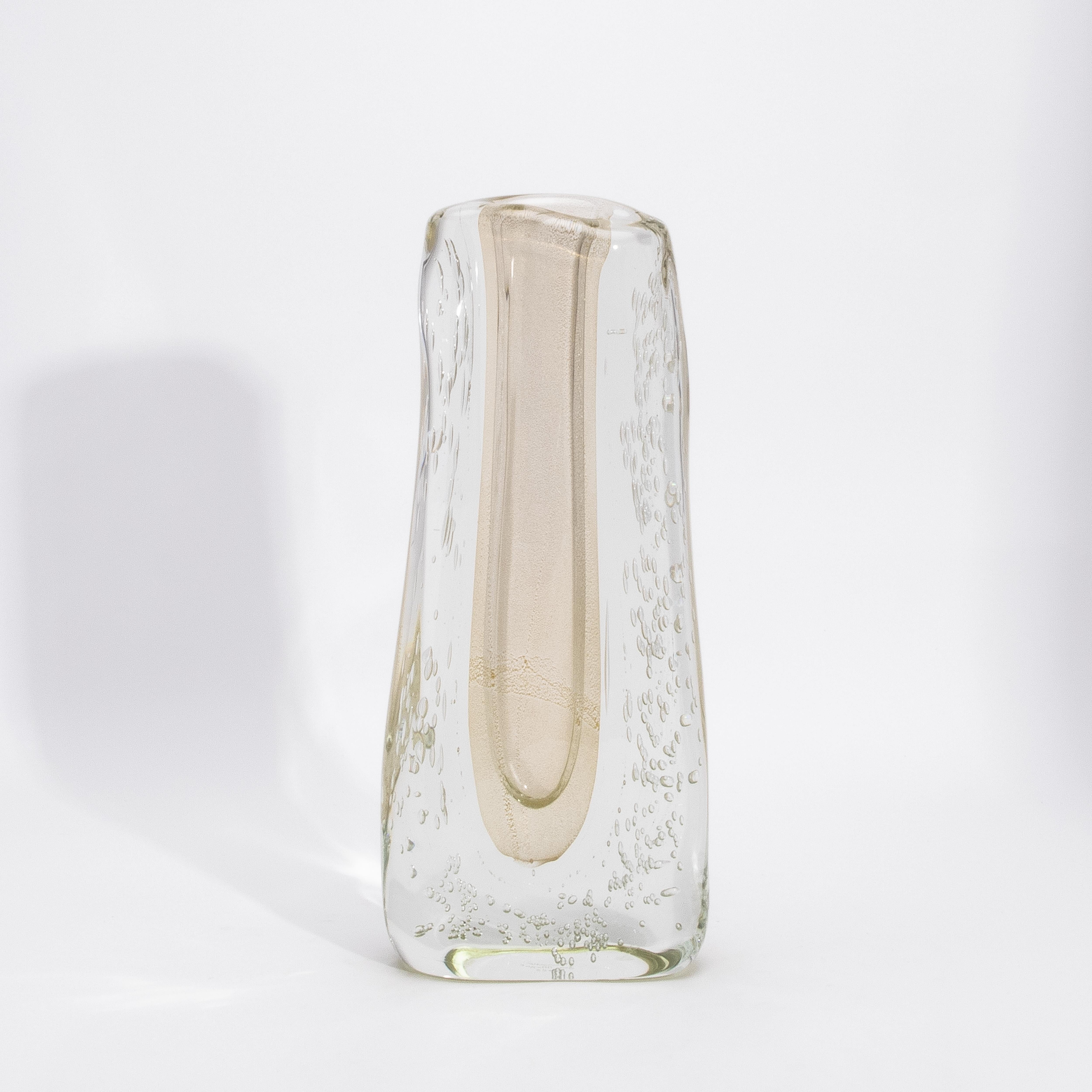 Incarnazione luminosa dell'arte del vetro di Murano, questo vaso fluido moderno di Murano soffiato a mano, trasparente con macchie e bolle d'oro a 24 carati, evoca un'eleganza senza tempo nella sua forma più raffinata. La morbida tonalità champagne,