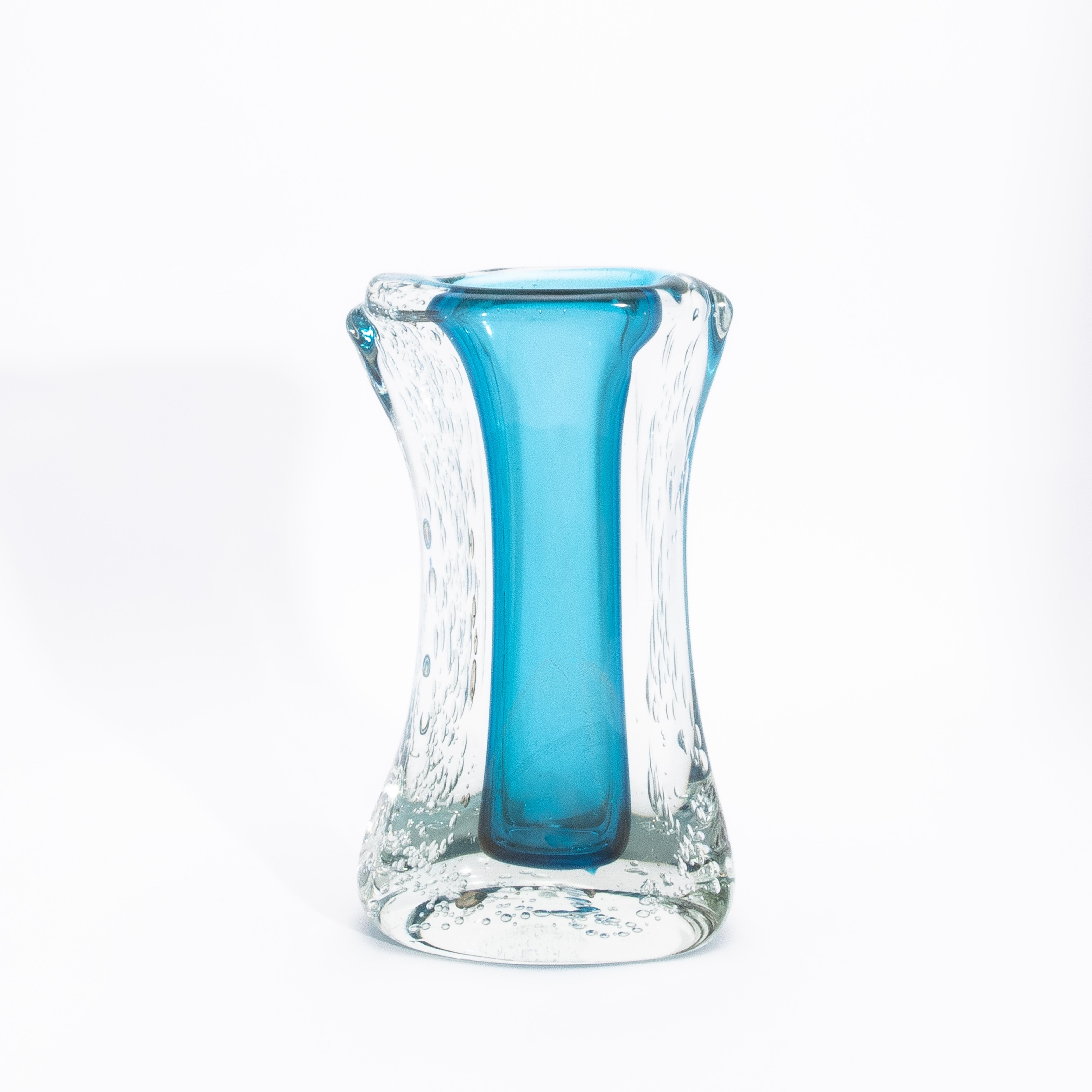 Diese mundgeblasene moderne Murano Fluid Vase in Aquamarinblau mit Blasen ist ein fesselnder Ausdruck zeitgenössischer Murano-Kunst und zeigt sich in einer skulpturalen Form, die das Wesen der fließenden Bewegung in der Zeit einfängt. Der leuchtende