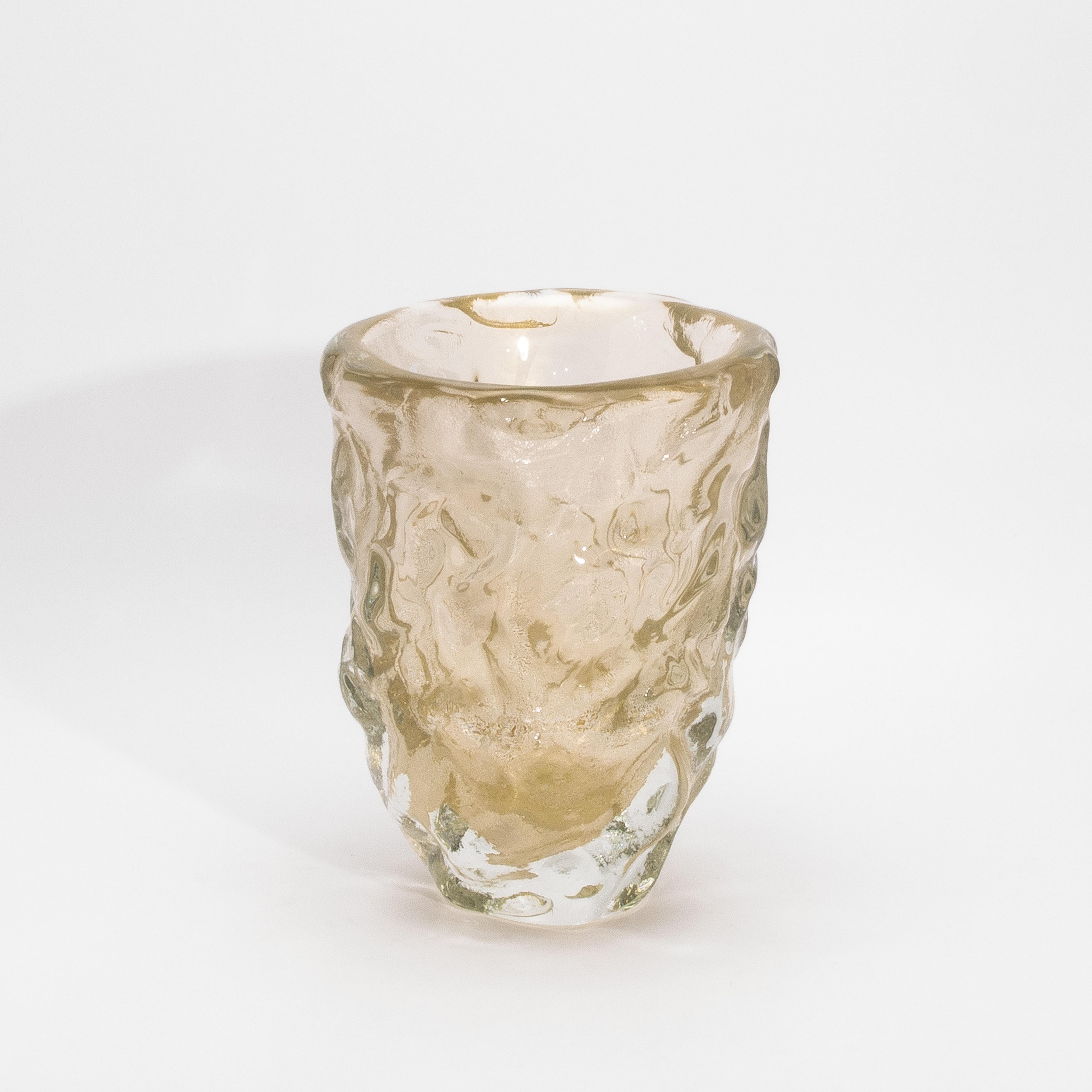 Un sorprendente tributo alla forma elementare, il Vaso scultoreo moderno di Murano soffiato a mano, trasparente con macchie d'oro a 24 carati, è un capolavoro di consistenza e luminosità. La sua superficie si increspa e si piega con spontaneità