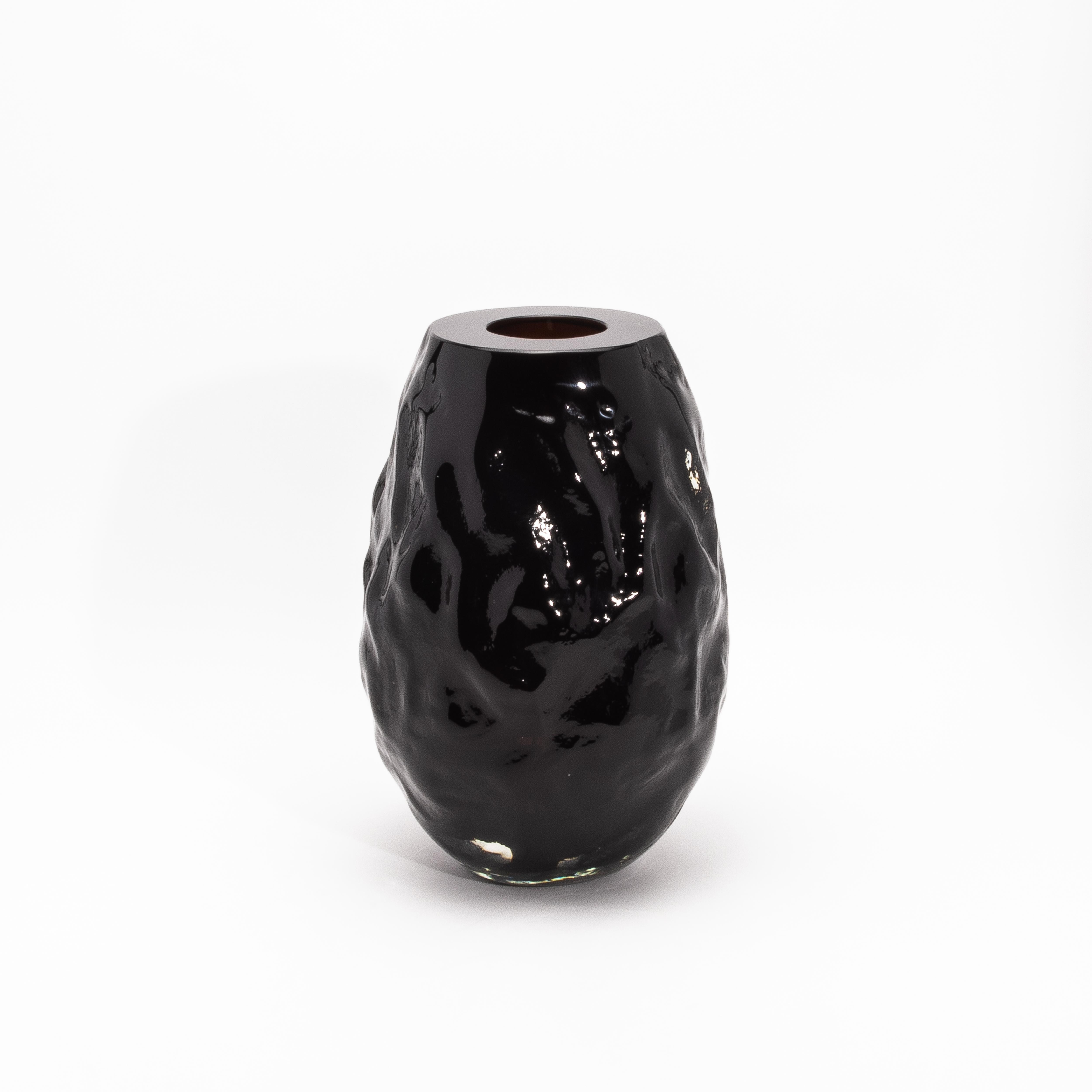 Questo vaso scultoreo di Murano soffiato a mano in nero onice è una celebrazione dell'artigianato moderno, dove la lavorazione tradizionale del vetro incontra il design contemporaneo. La sua superficie è riccamente strutturata, con una forma