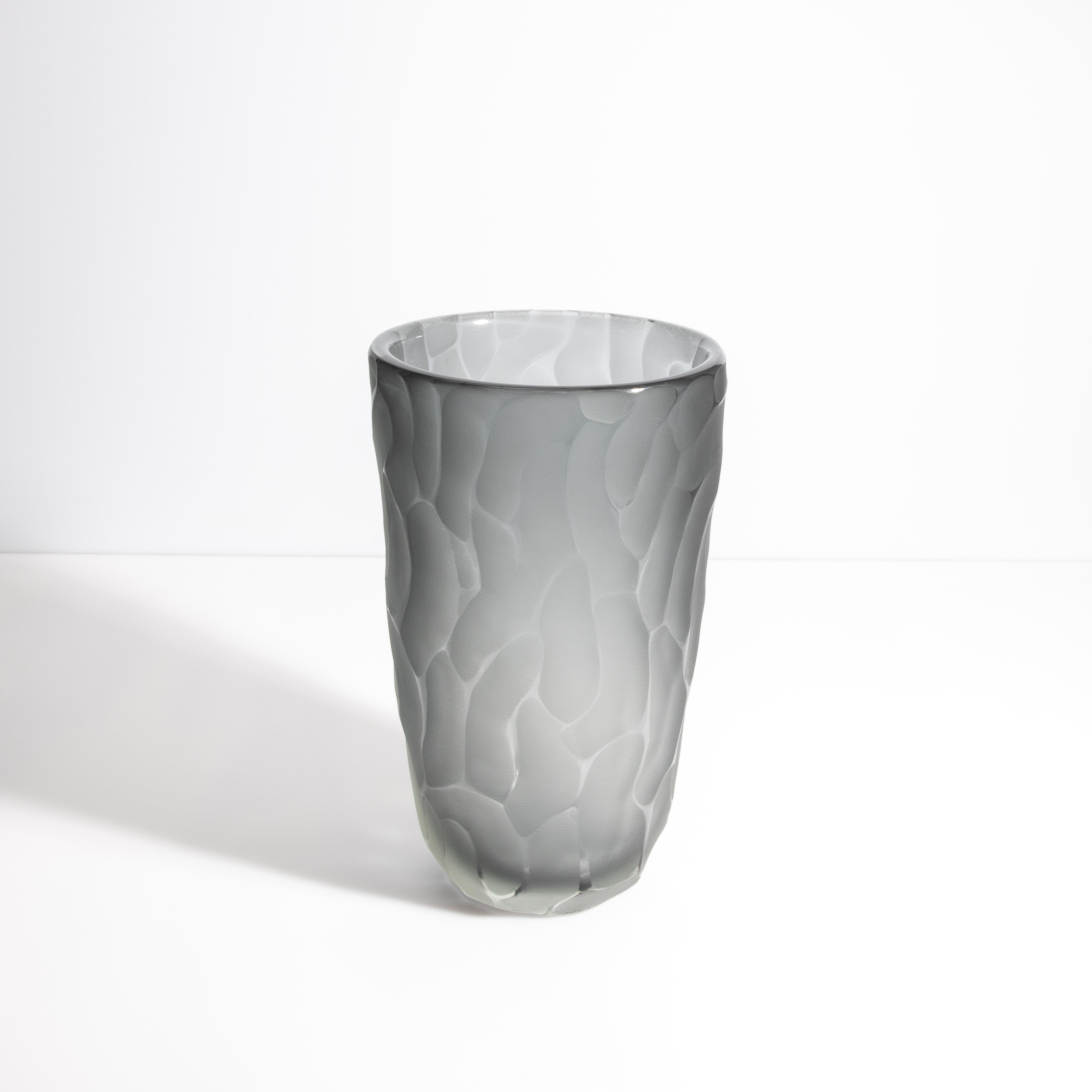 Questo squisito vaso vanta una lussuosa finitura grigia opaca che contrasta elegantemente con la sua superficie intricata, che ricorda i raffinati motivi presenti in natura. La texture unica crea un'esperienza visiva e tattile coinvolgente,