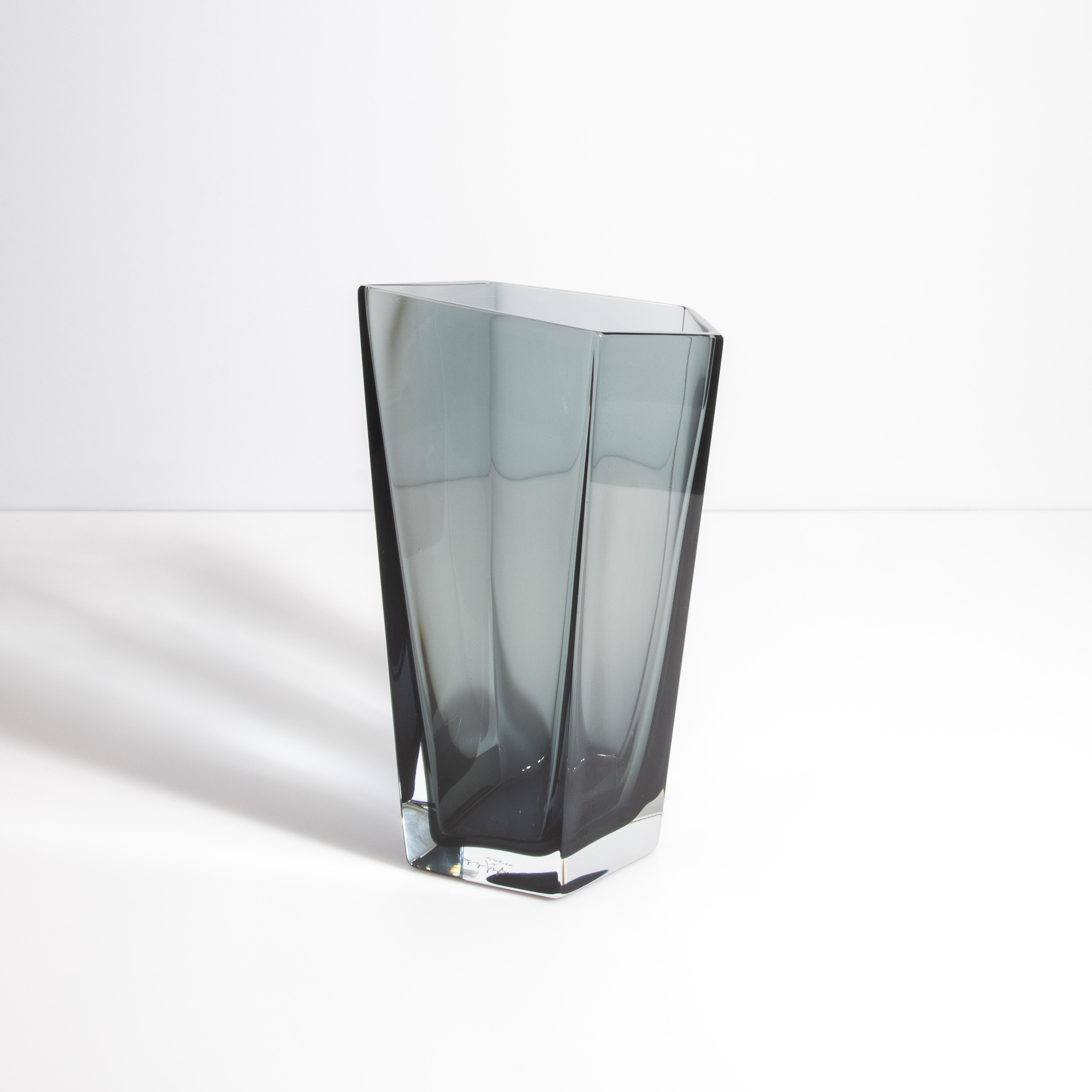 Ti presentiamo il vaso Penta Grey Murano, un pezzo squisito che incarna l'arte e l'eleganza della lavorazione del vetro veneziano. Questo vaso si distingue per la sua forma pentagonale e le sue linee eleganti, creando un look moderno e sofisticato.