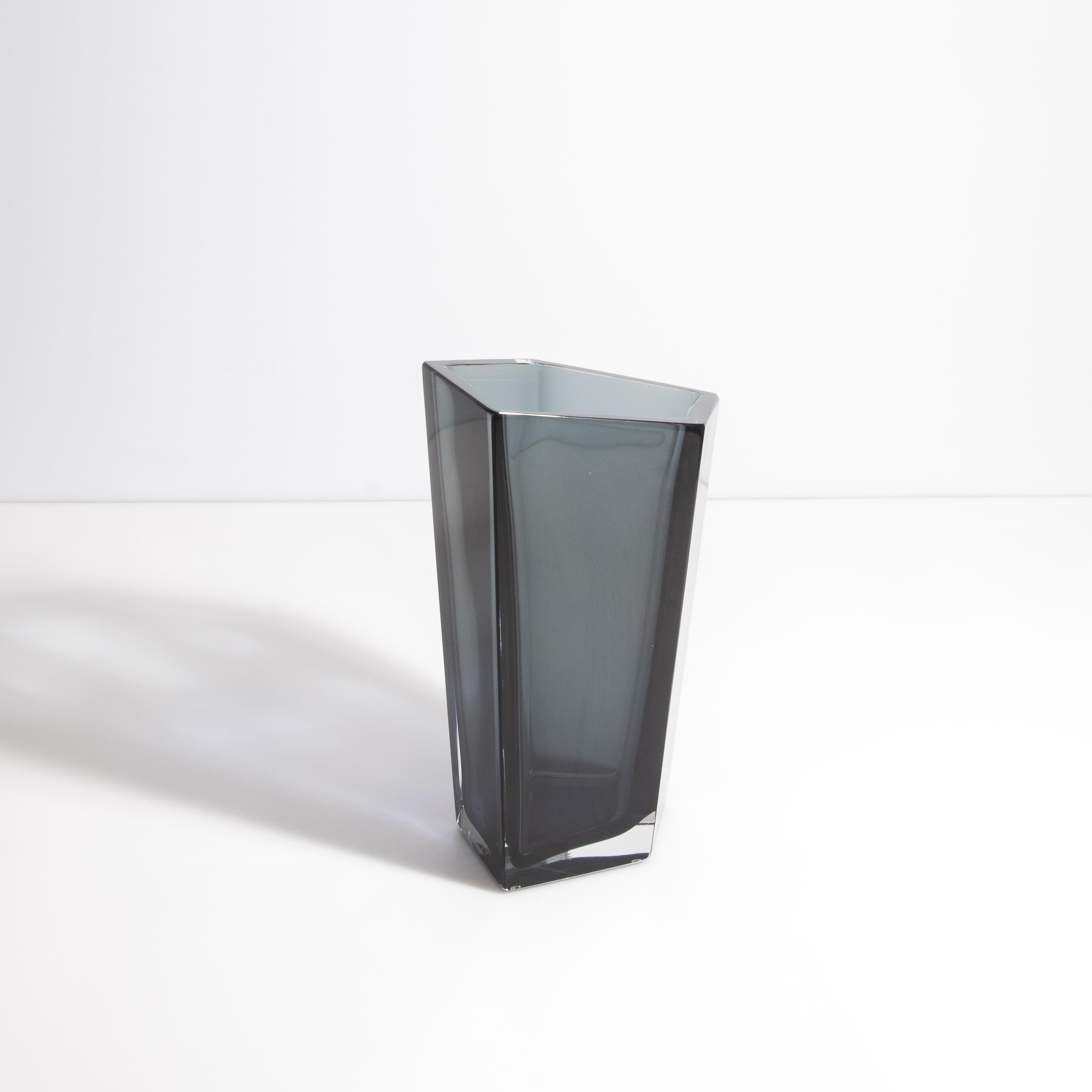 Questo squisito vaso pentagonale di Murano è un vero capolavoro del lusso e dell'artigianato italiano, realizzato meticolosamente dai migliori soffiatori di Murano, in Italia. Questo vaso, in una splendida tonalità di grigio, è una testimonianza