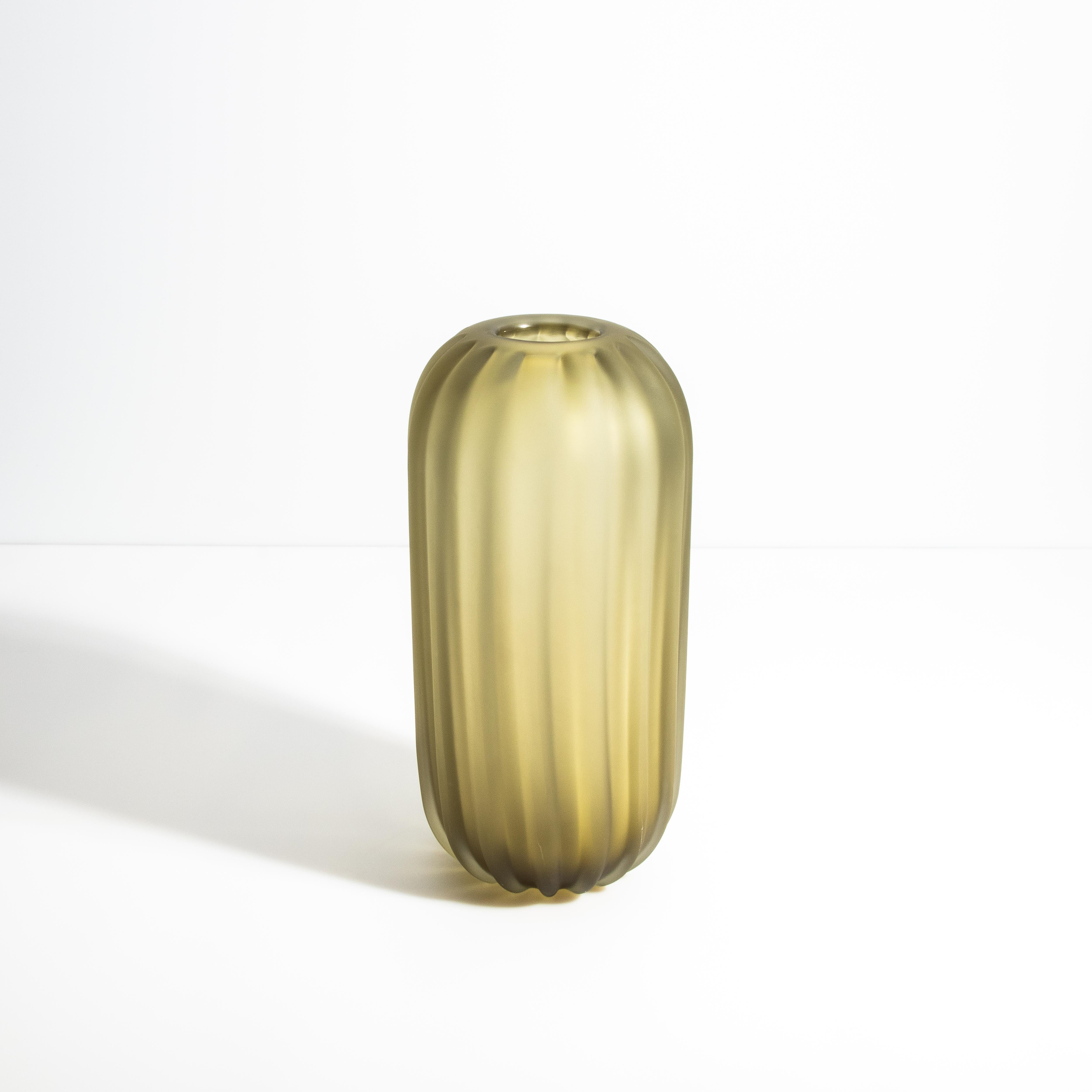 Ispirato alla bellezza naturale del deserto, questo vaso in vetro di Murano cattura l'essenza dell'eleganza e della semplicità. La finitura opaca color oliva e la texture a coste richiamano le linee organiche di un cactus del deserto, unendo il